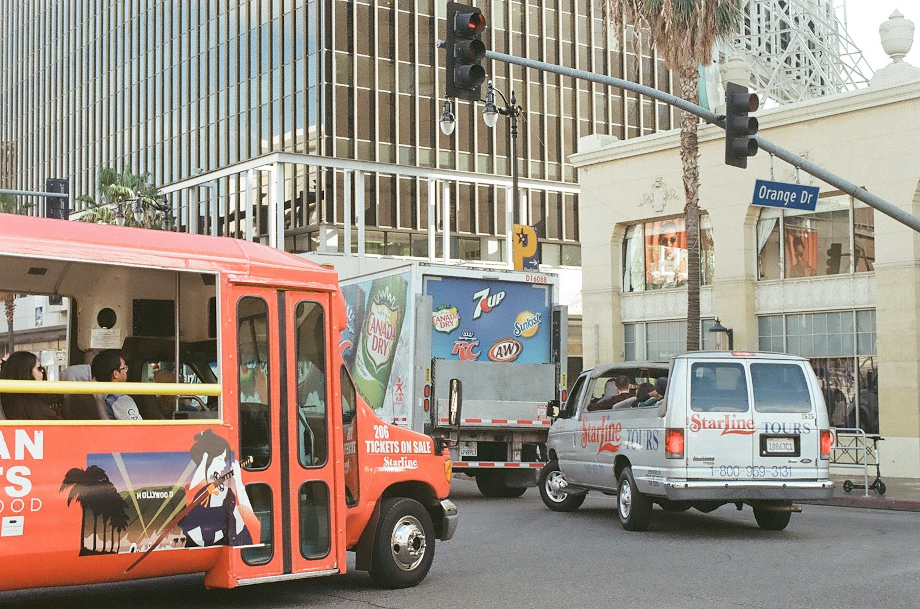 Red bus and truck intersecting at a traffic light in a city