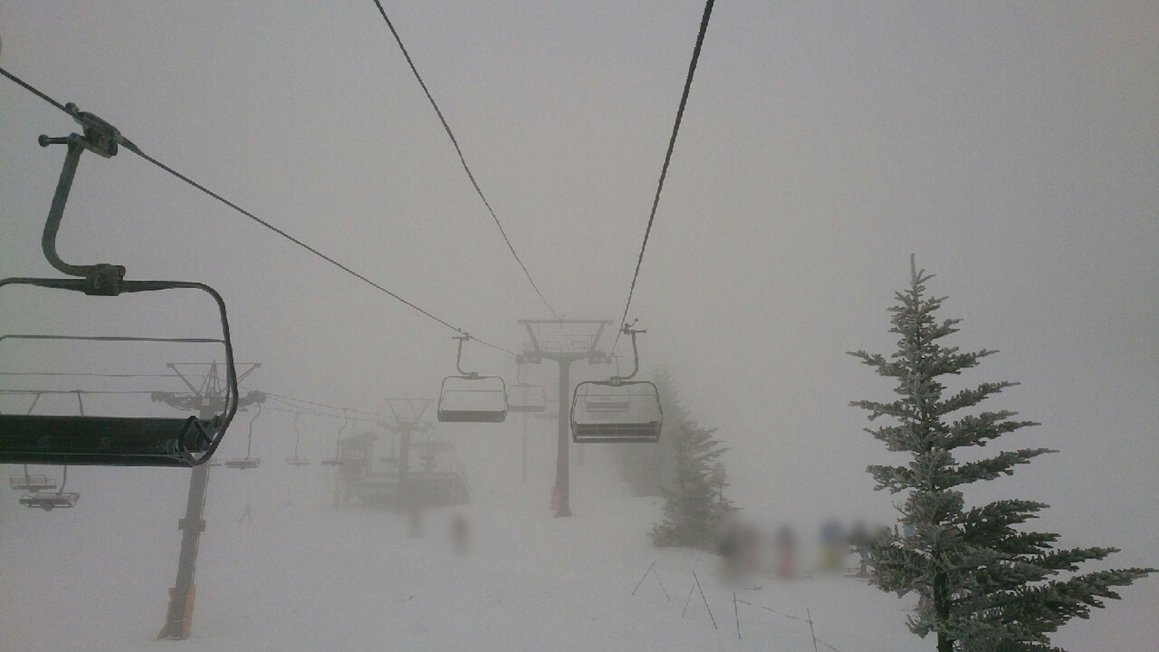 Escena de telesilla cubierto de nieve con árboles en la niebla