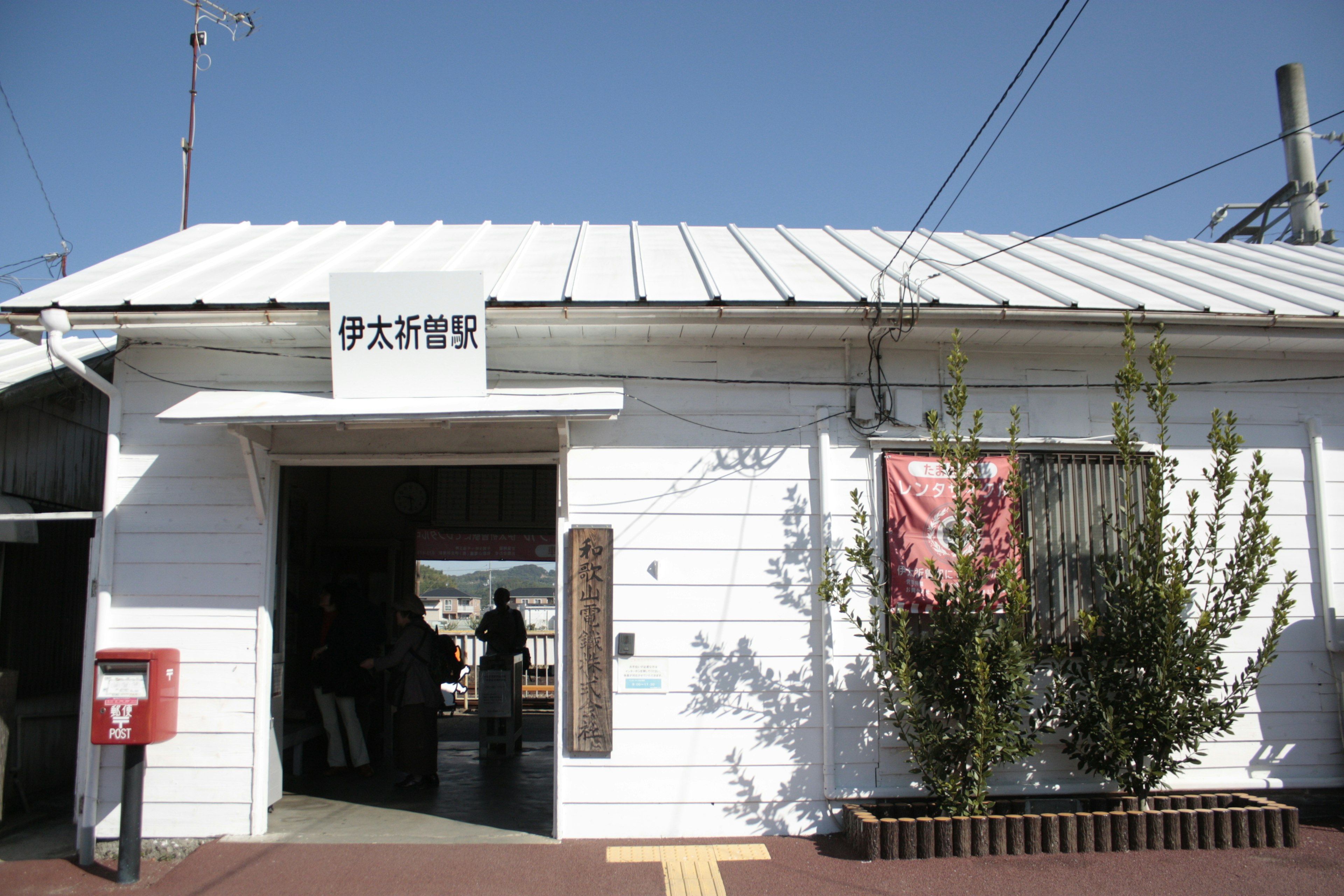 White exterior train station building with a red mailbox