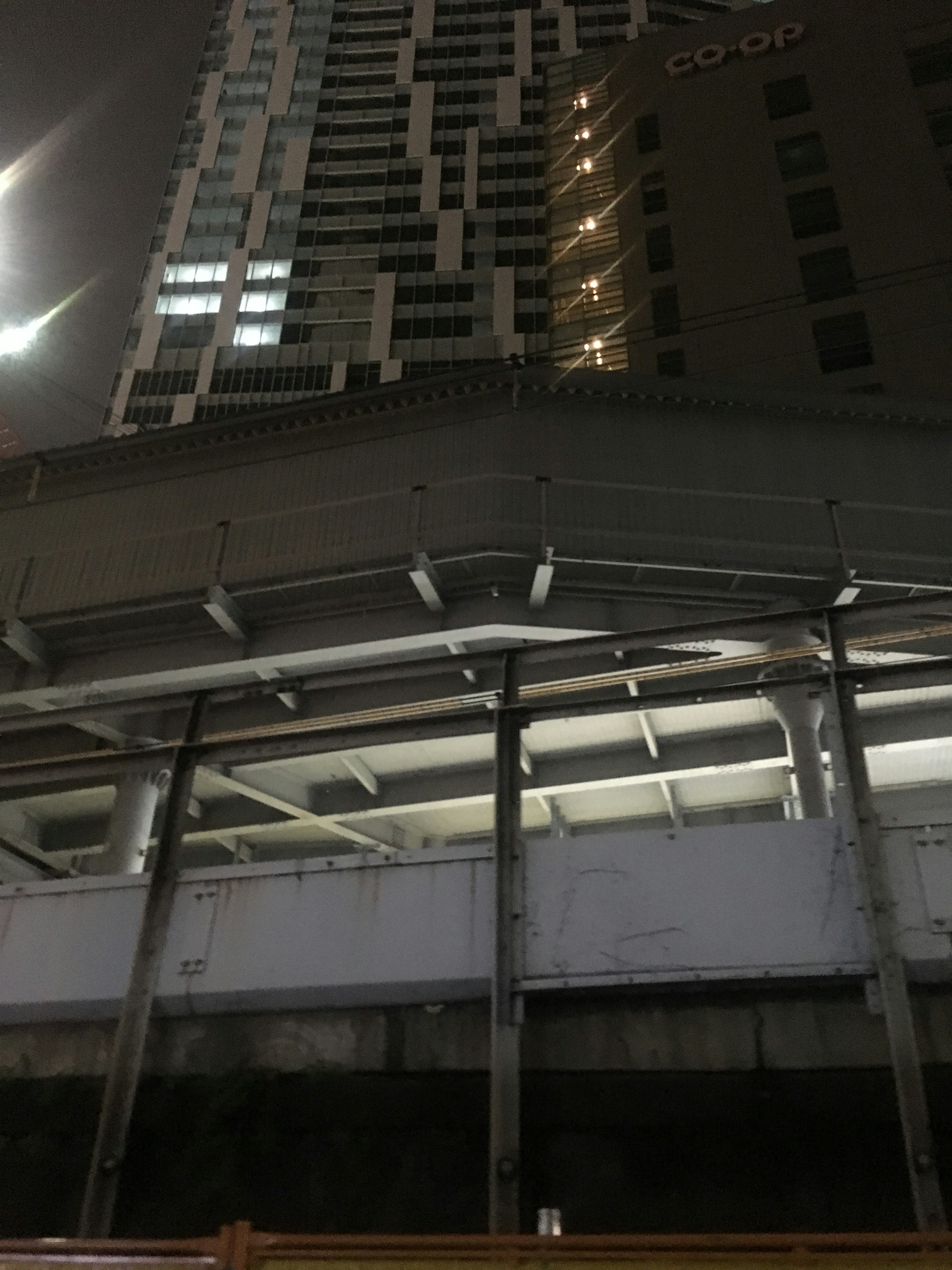 Paisaje urbano nocturno con edificios altos y un paso elevado