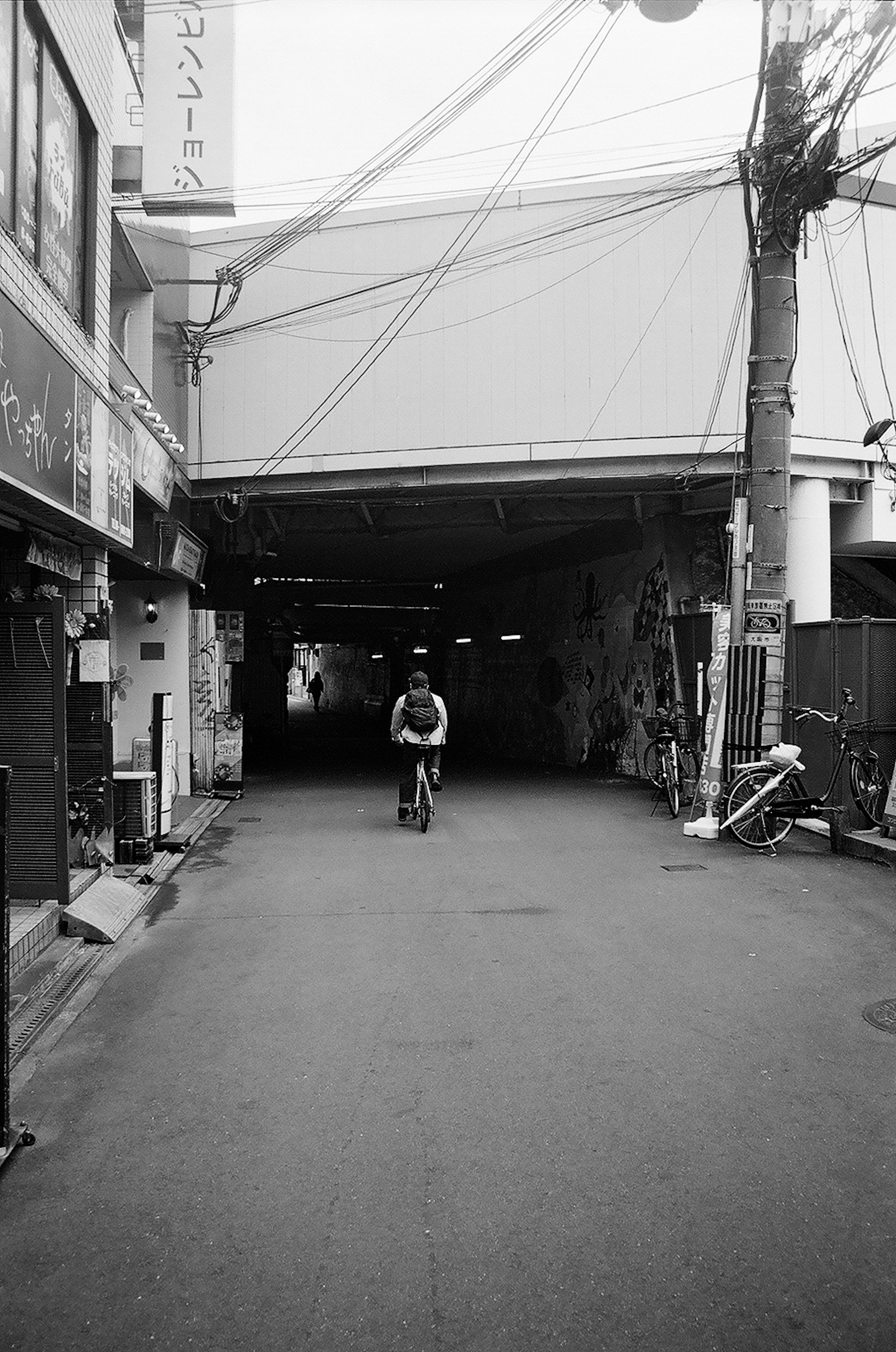 Una persona montando una bicicleta en una calle de la ciudad que lleva a un túnel oscuro