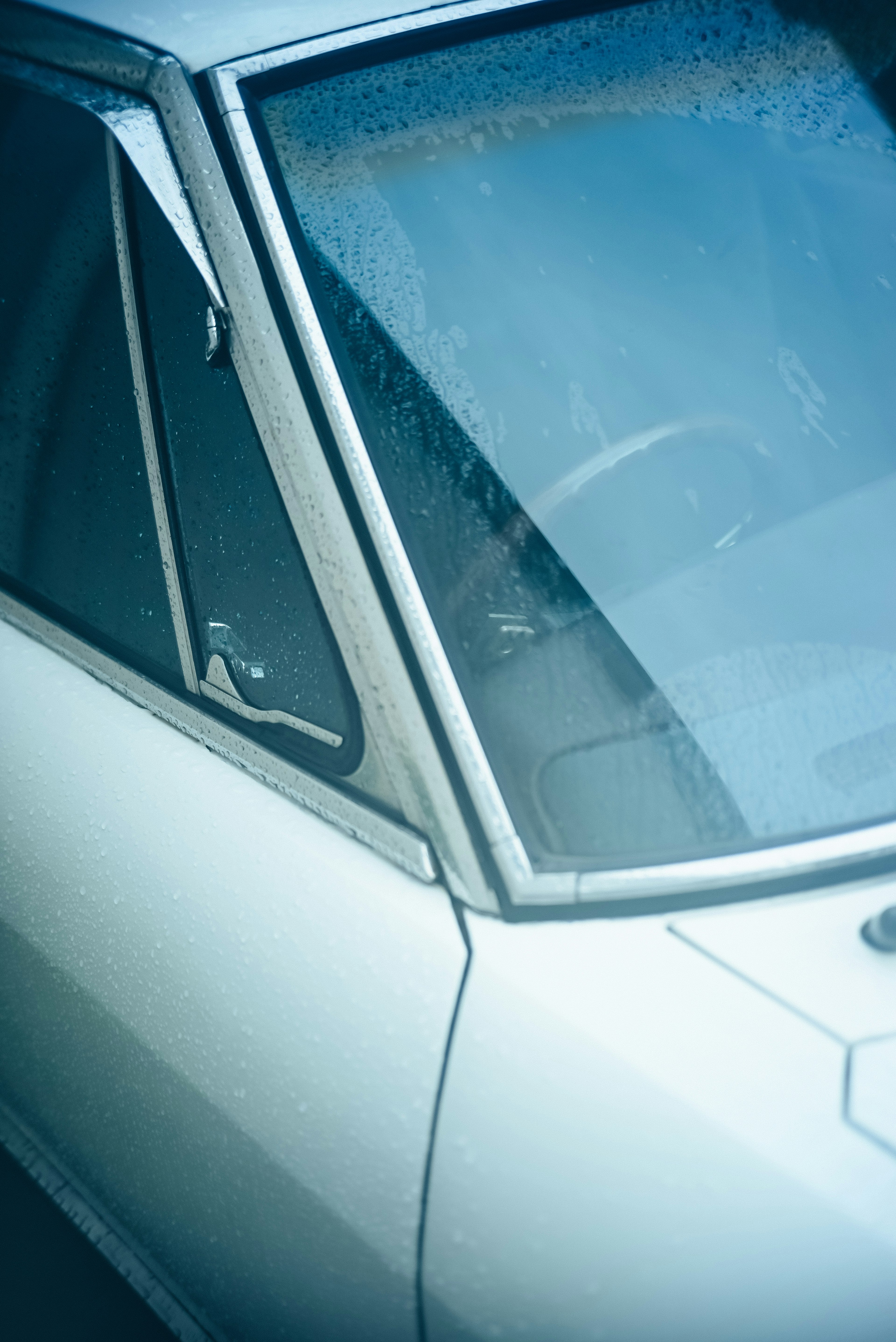 Close-up of a vintage car with a blue background and water droplets