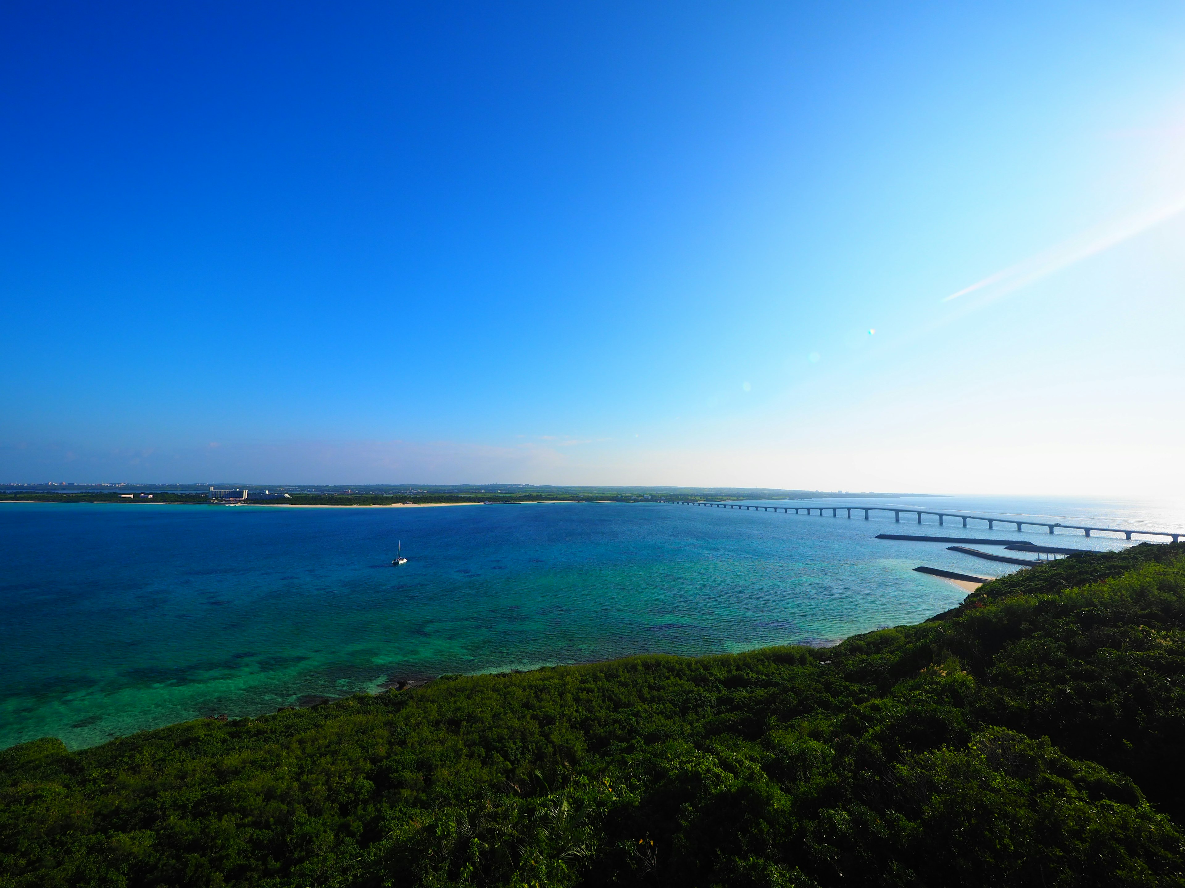 Vista escénica del cielo azul y el océano vegetación verde y un puente