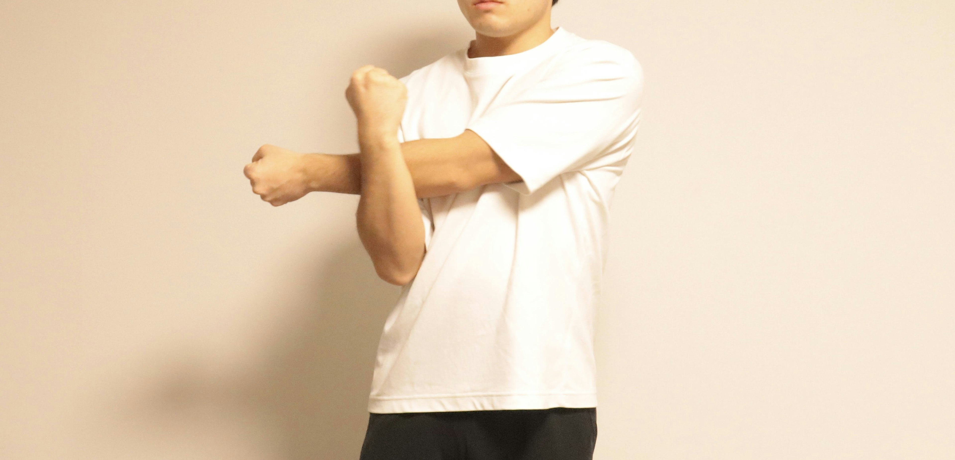 A man in a white t-shirt stretching his arms