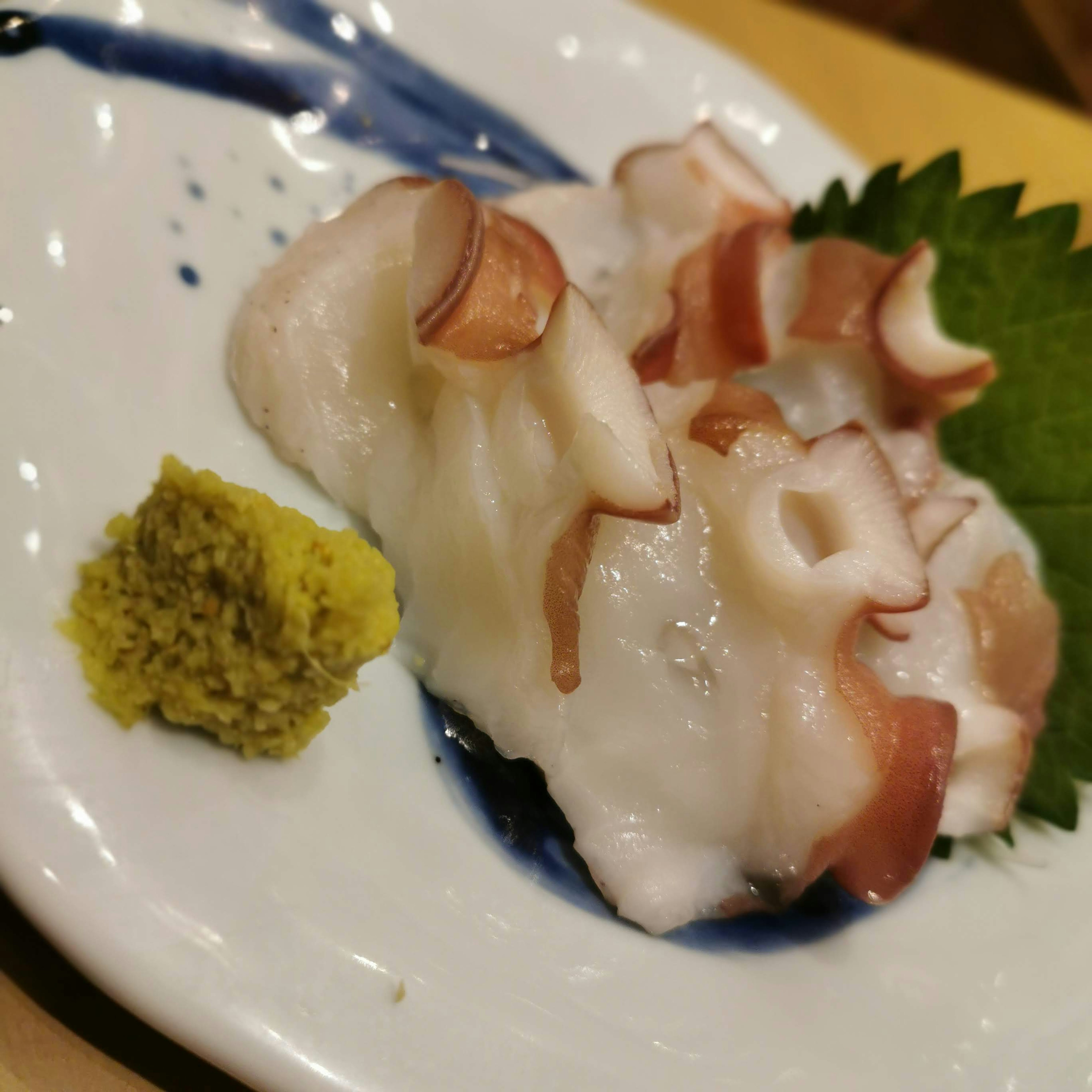 Sashimi gurita disajikan di atas piring dengan wasabi