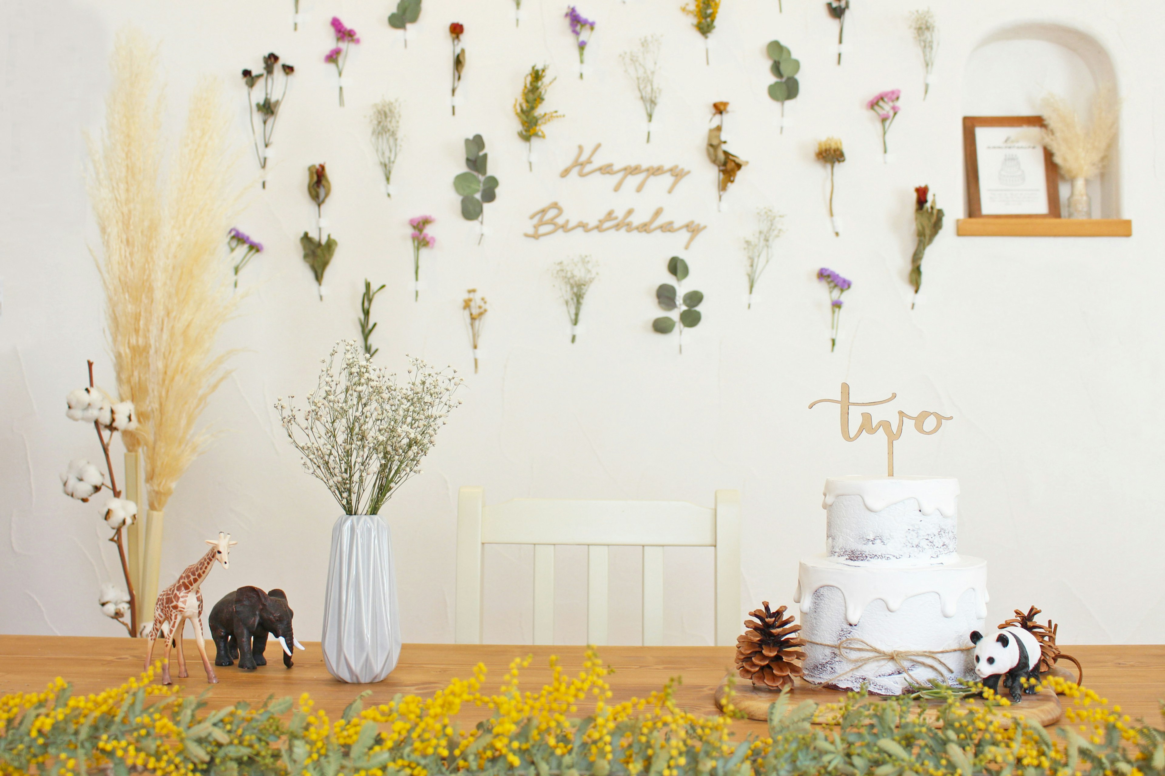 Table lumineuse décorée pour un anniversaire avec un gâteau blanc et des fleurs disposées