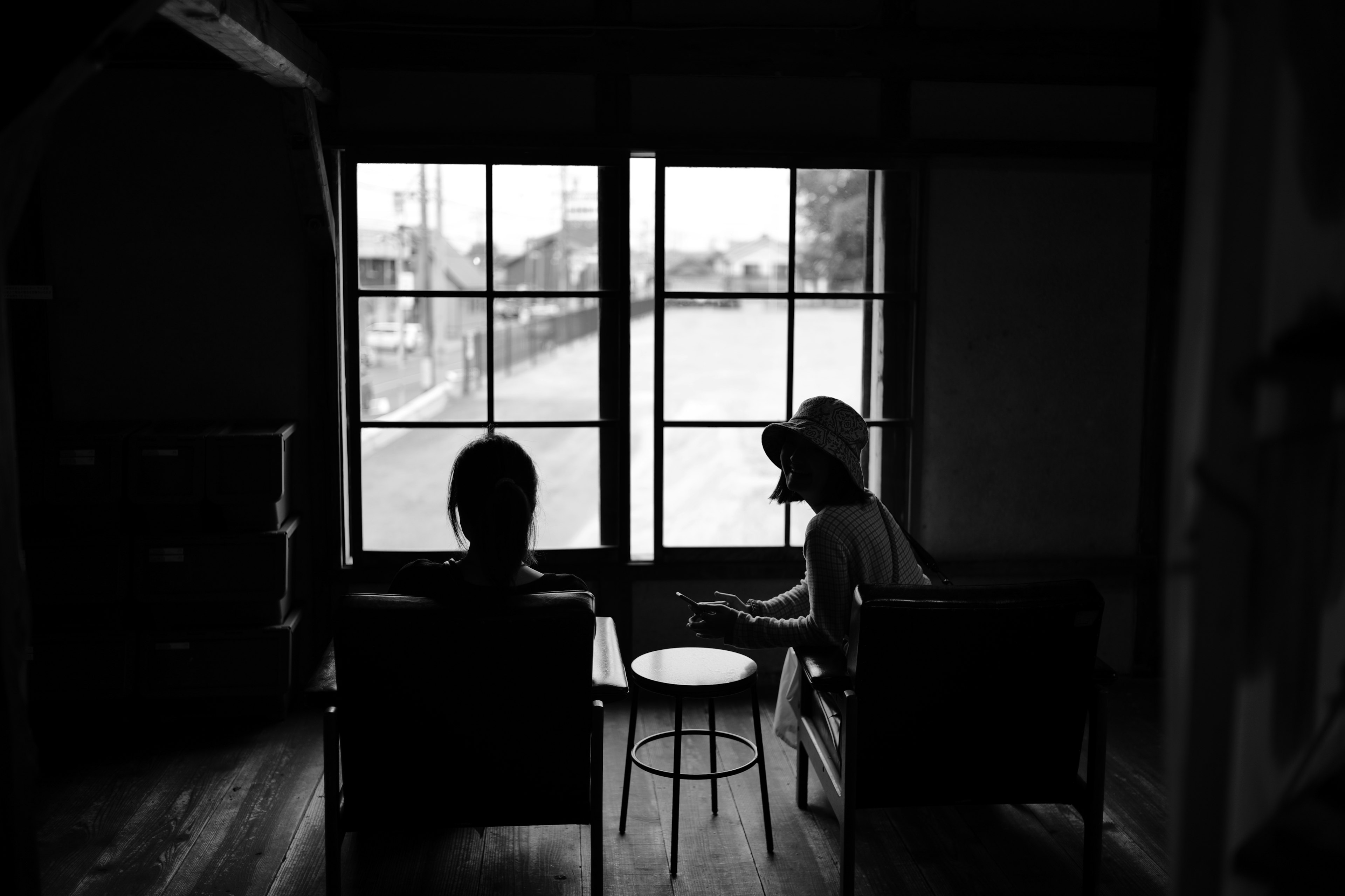 Dos figuras sentadas cerca de una ventana en una foto en blanco y negro