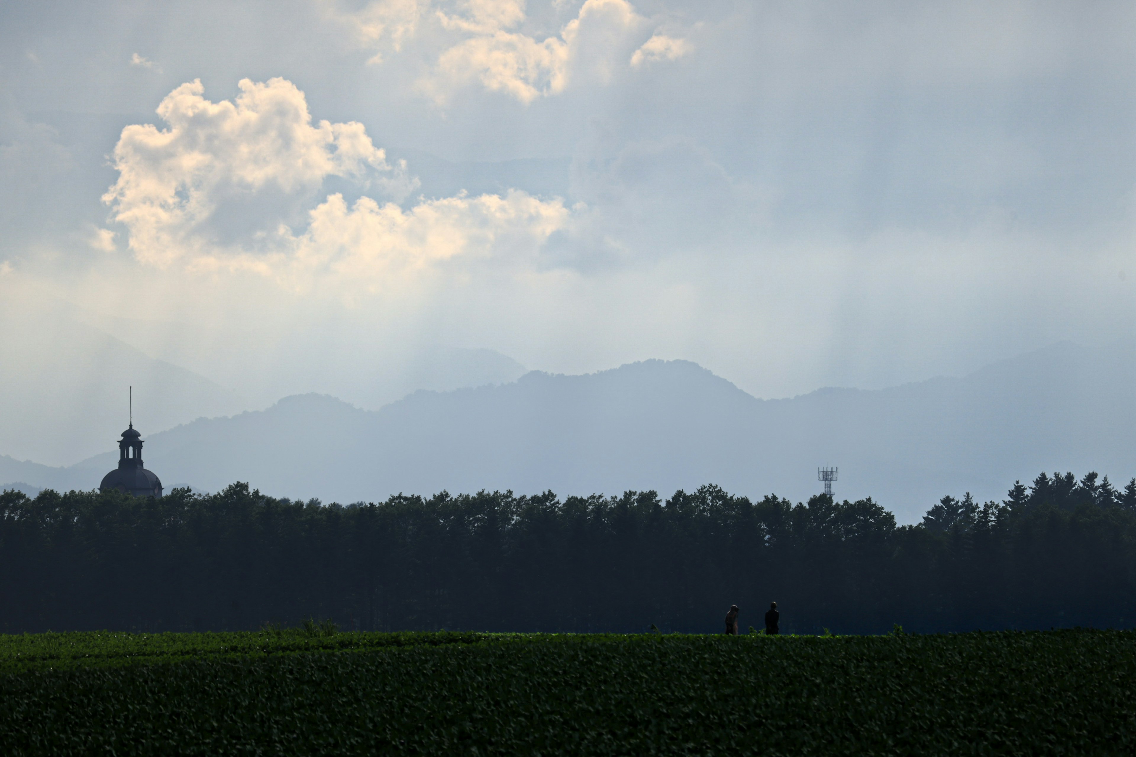 遠くの山々と雲のある風景に人々が歩いている