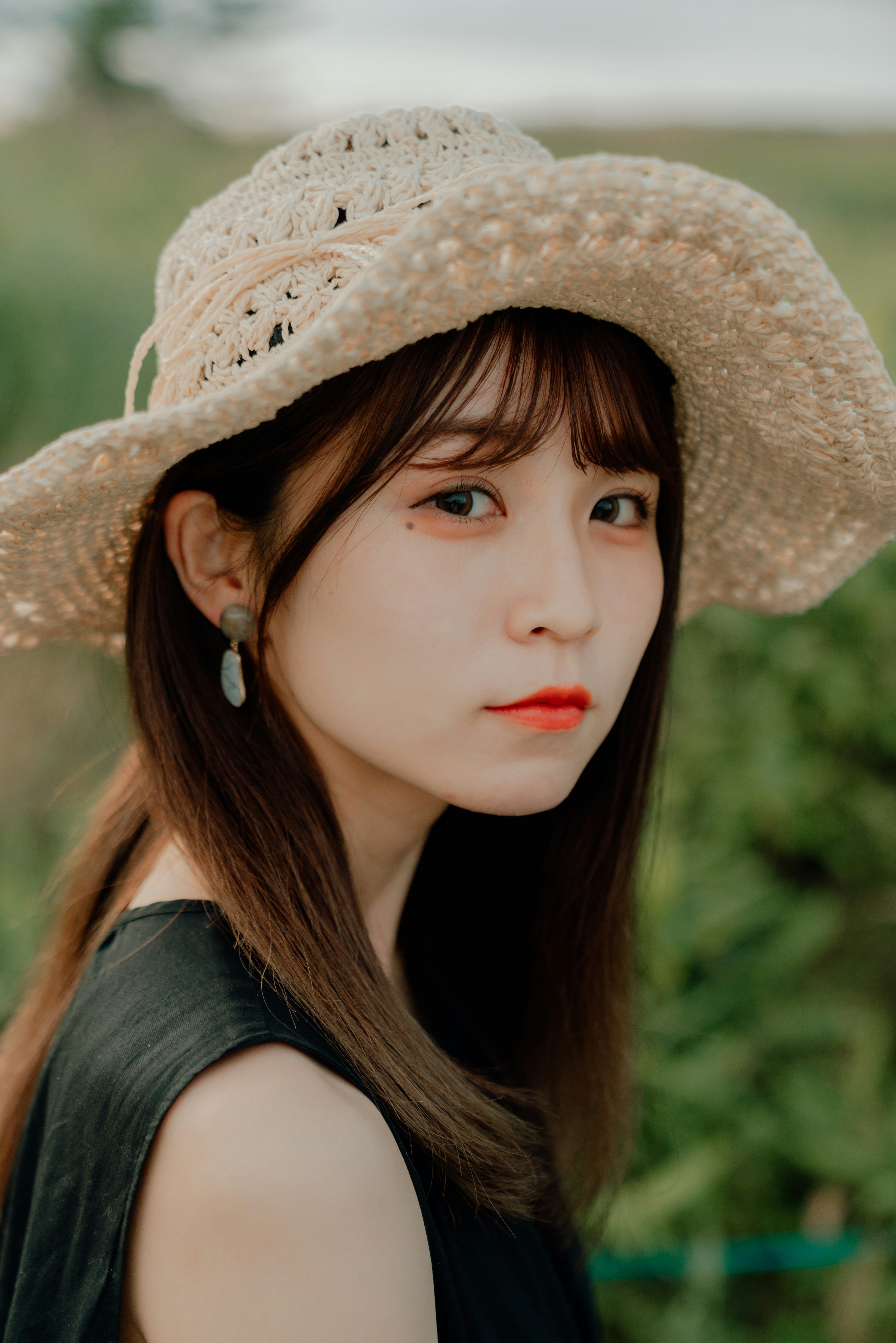 Profile of a woman wearing a straw hat with a green background