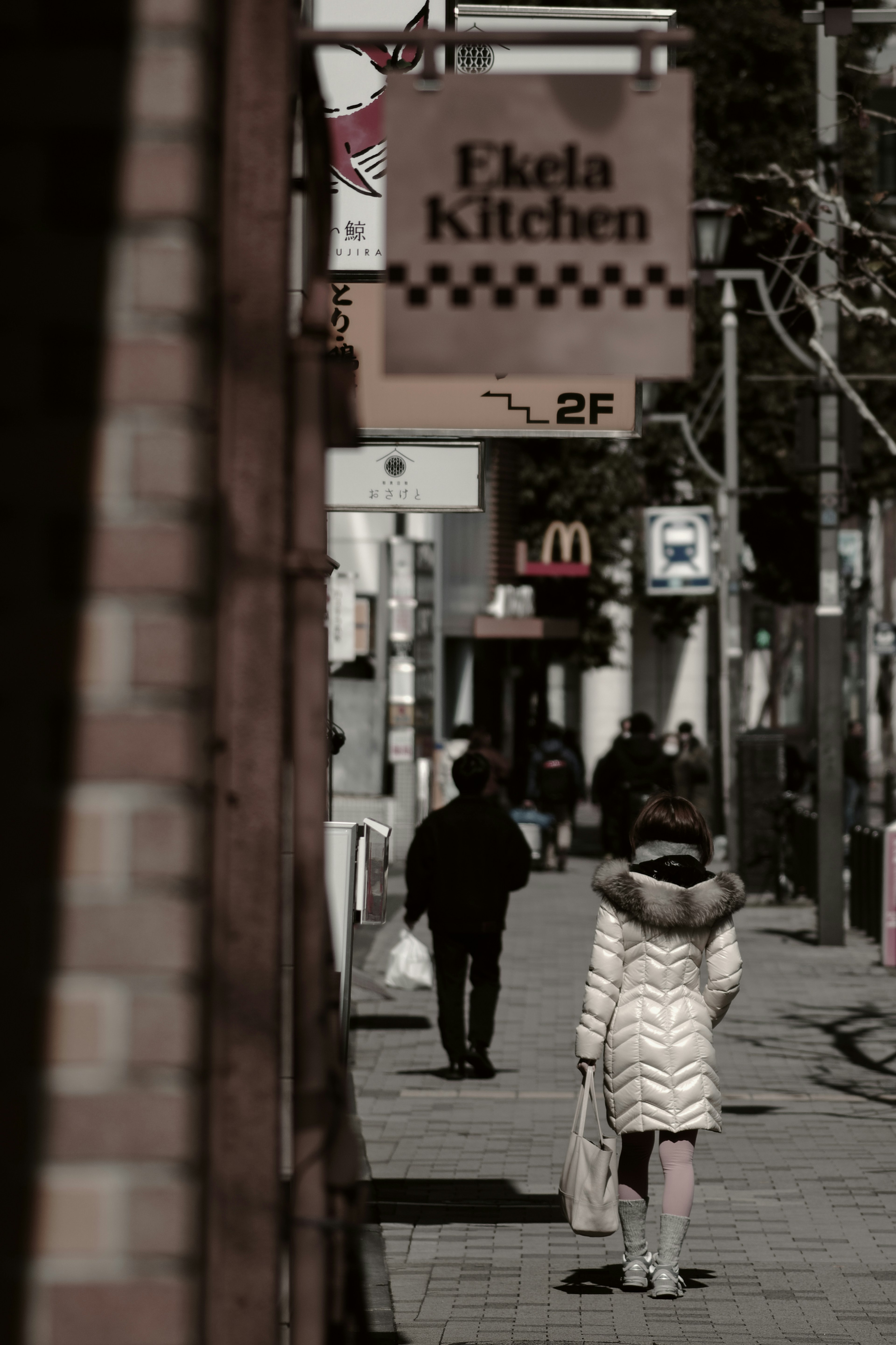 Persone che camminano lungo una strada con un'insegna di Eclair Kitchen