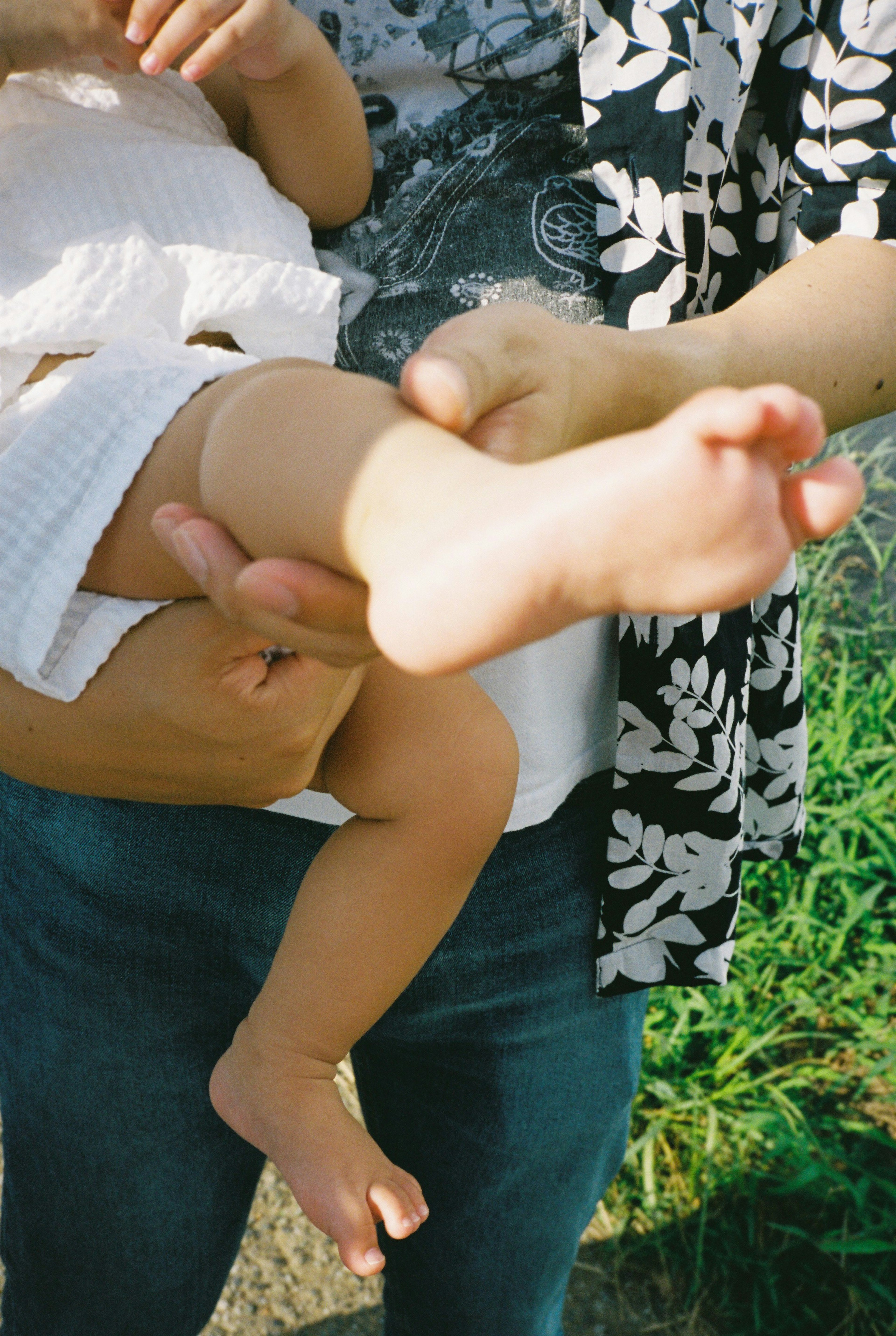 Parent holding baby's foot with green background