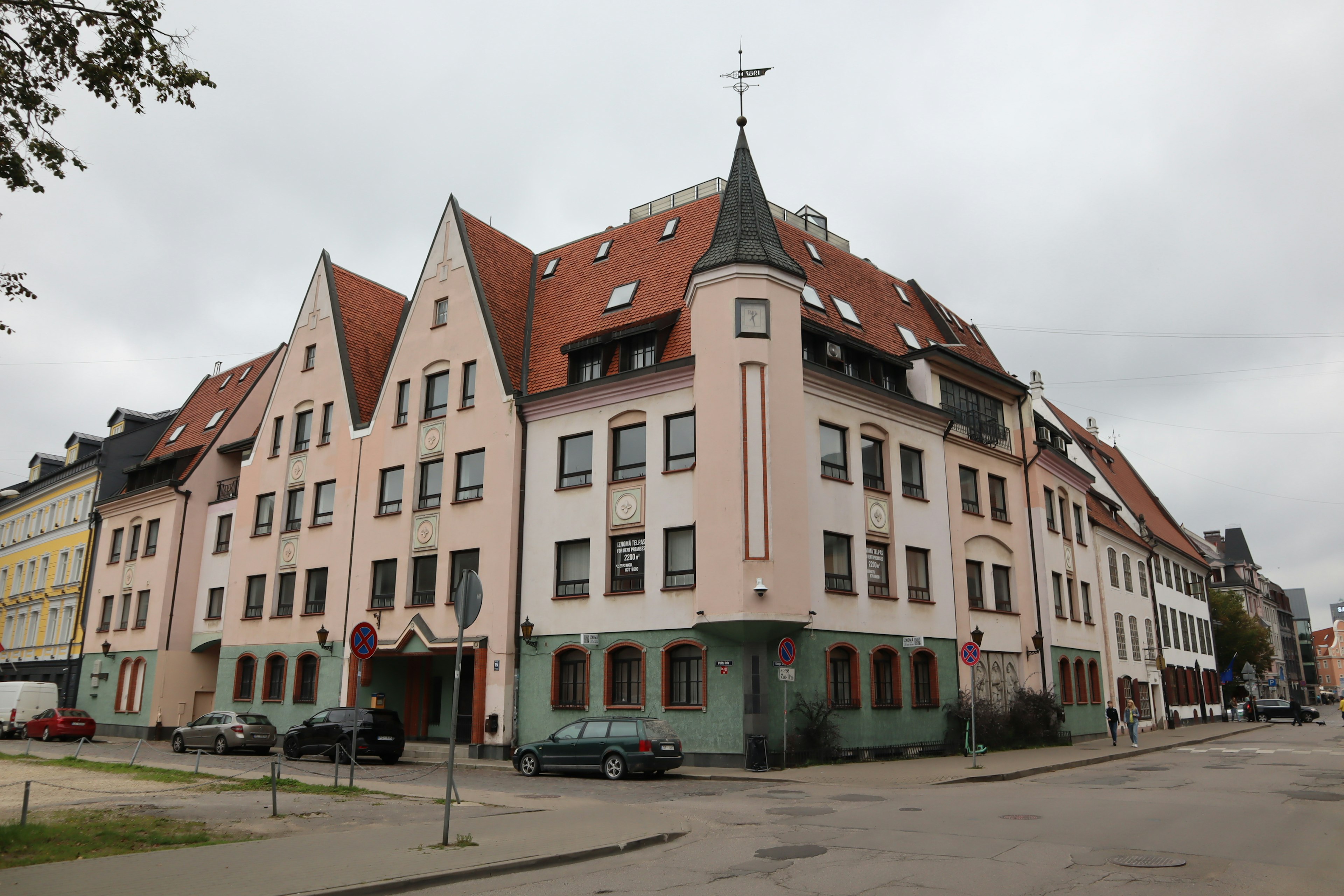 Corner view of a building with red roofs and pink facade