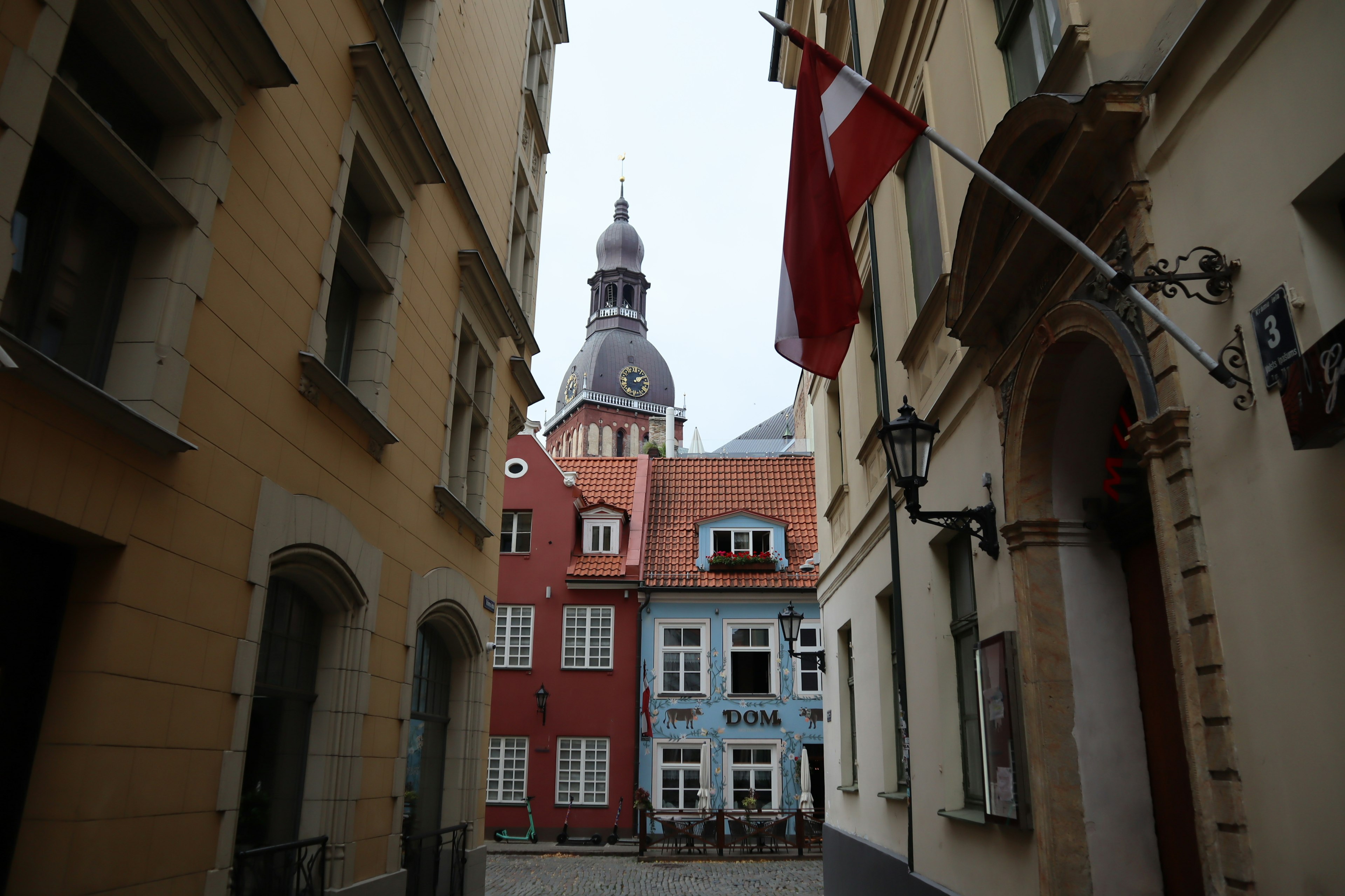 Narrow street flanked by colorful buildings and a church dome