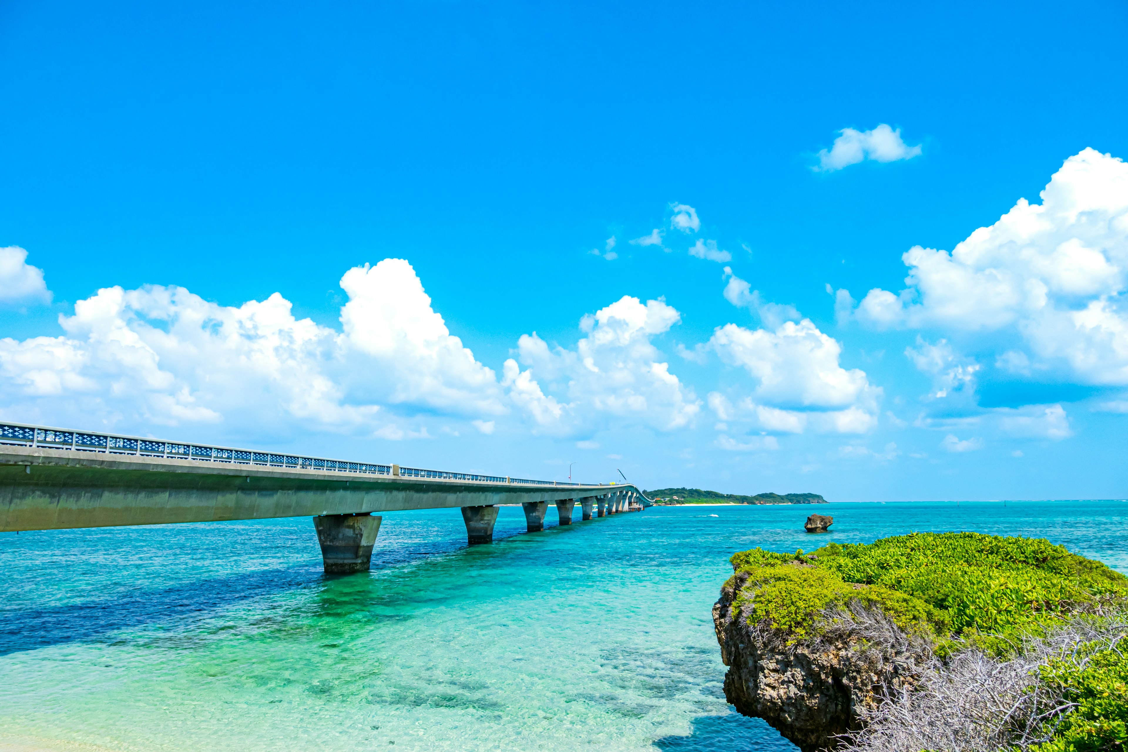 Pemandangan jembatan di atas air biru jernih dengan awan cerah