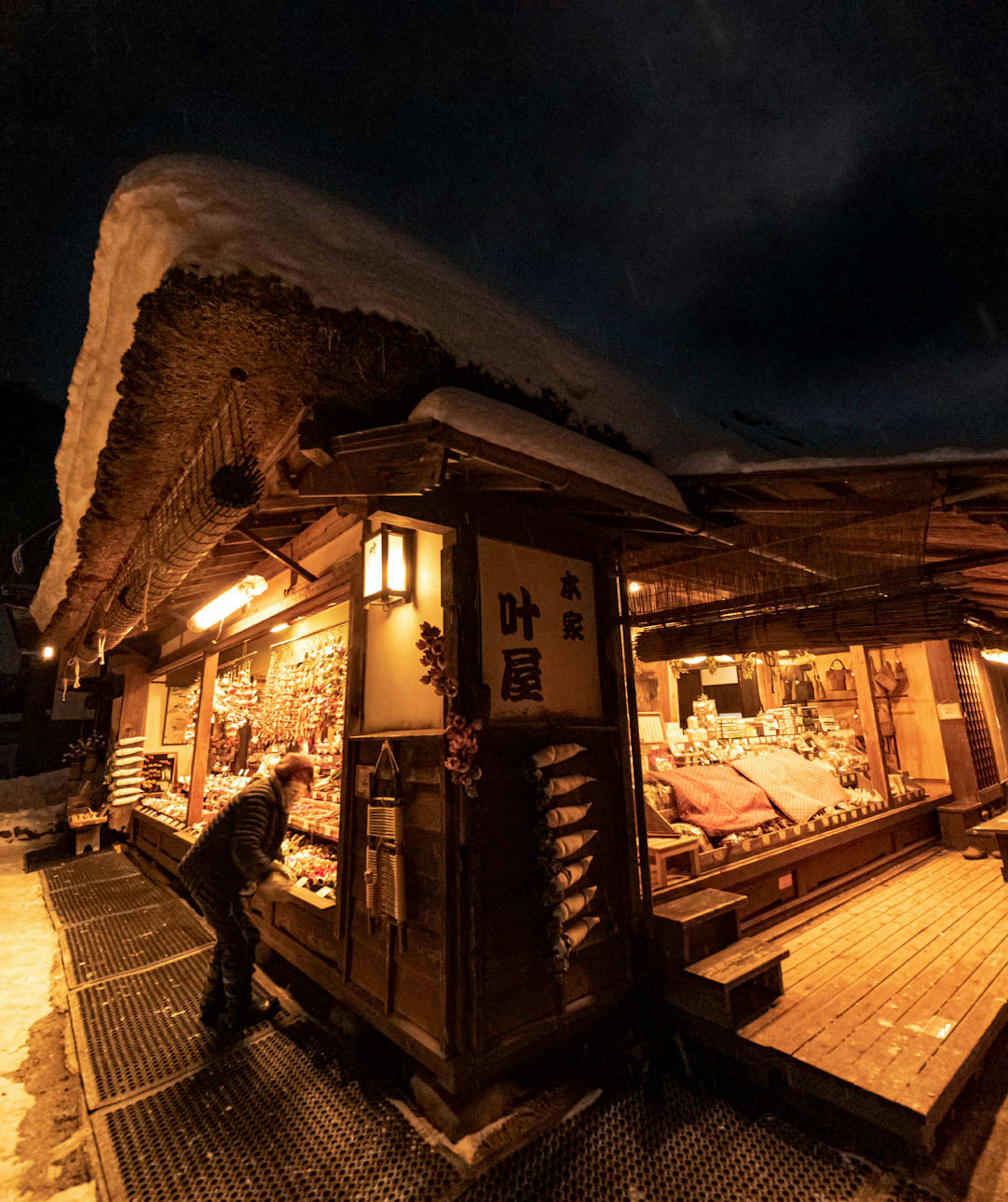 雪に覆われた伝統的な日本の店舗が夜に照らされている