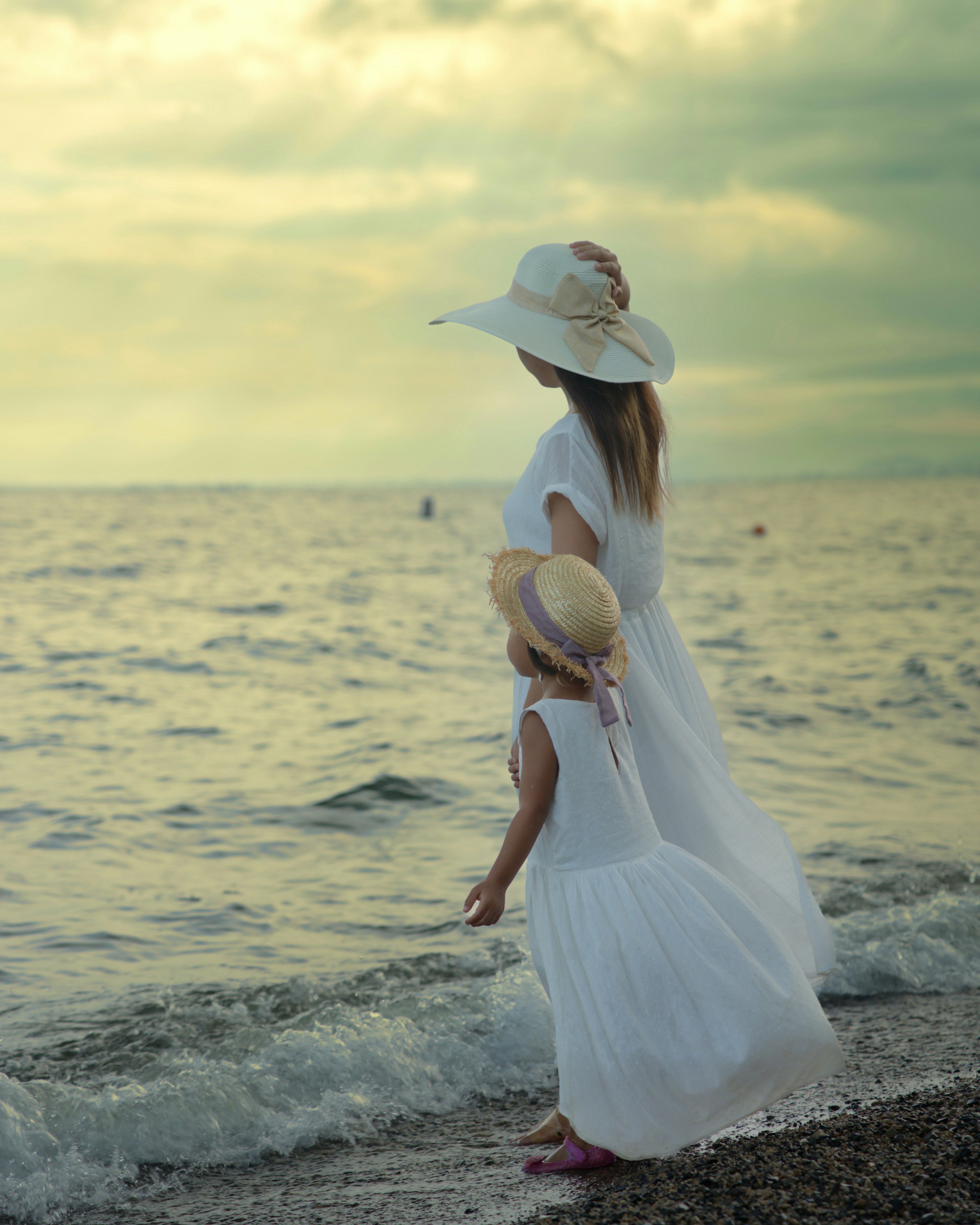 Una madre e una figlia in vestiti bianchi sulla spiaggia