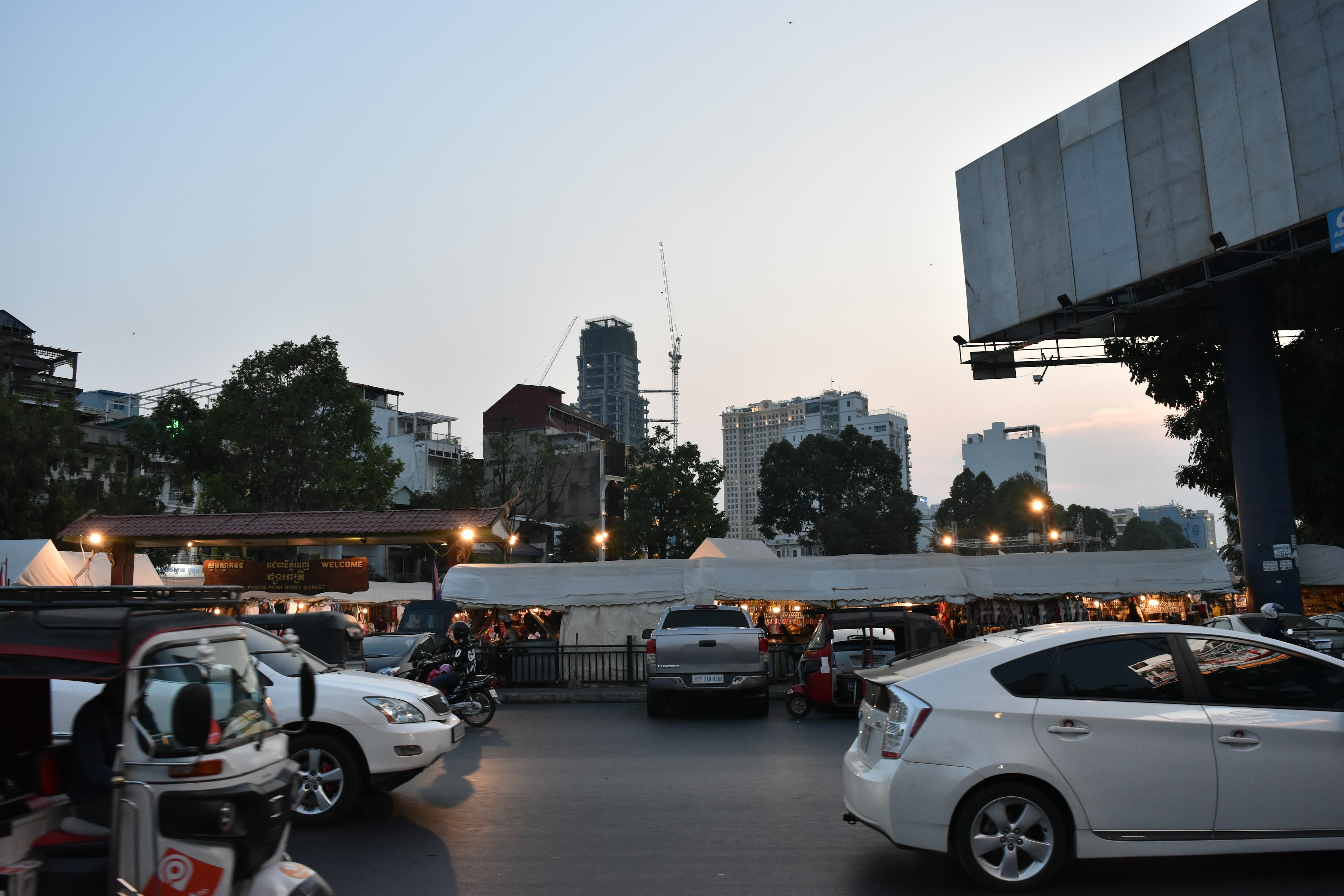 Pemandangan kota saat senja dengan mobil terparkir dan siluet gedung pencakar langit