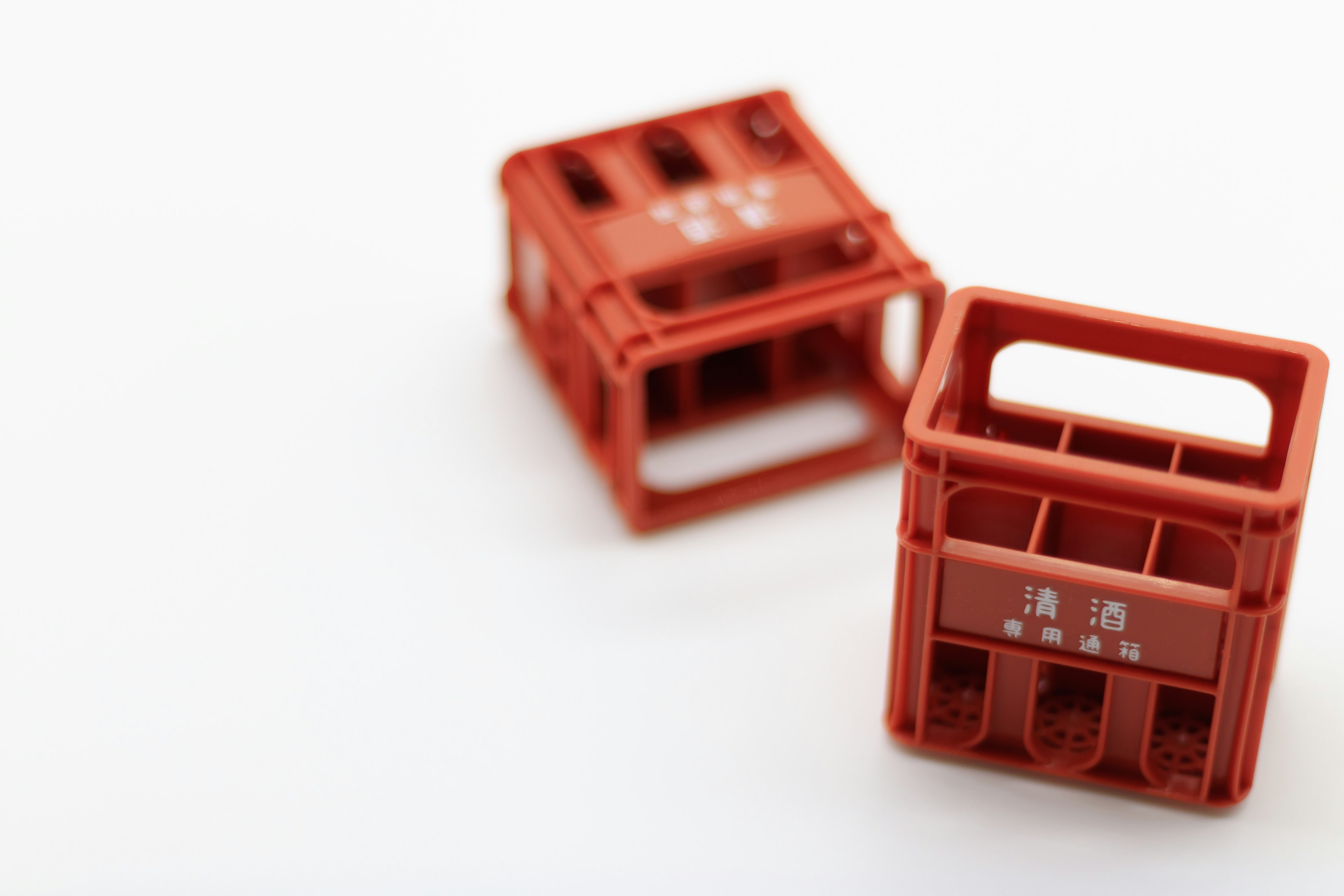 Two small red plastic crates positioned on a white background