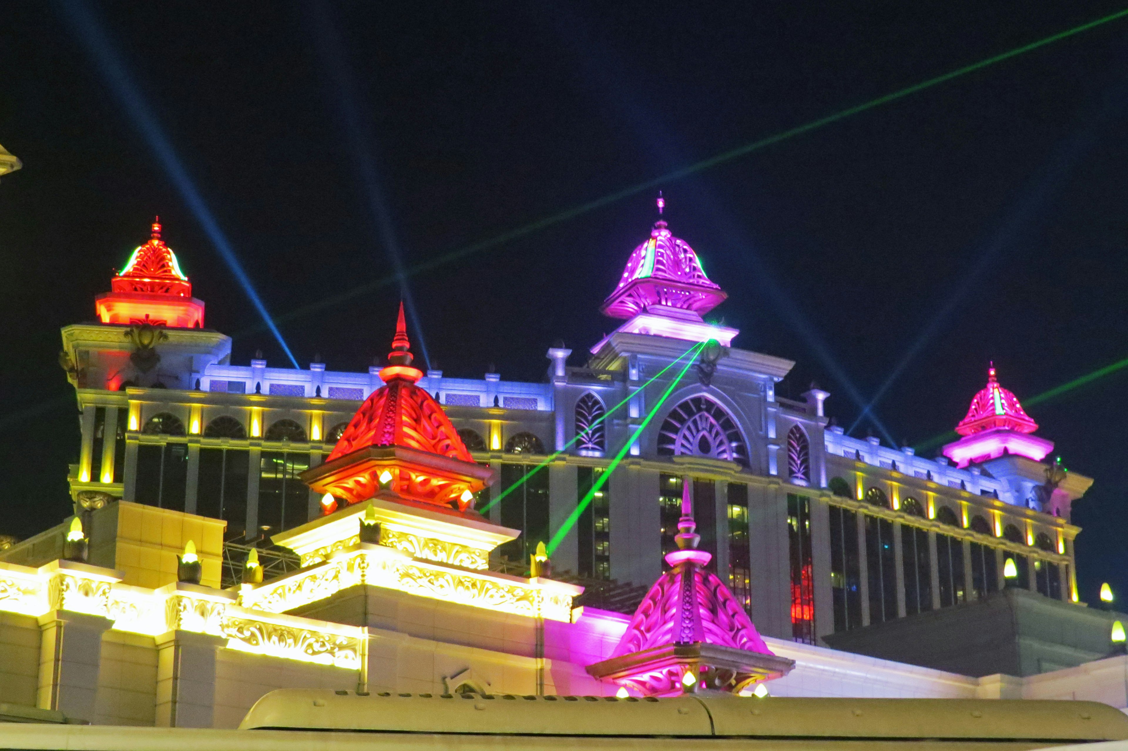 Illuminated building at night featuring red and purple lights with laser beams