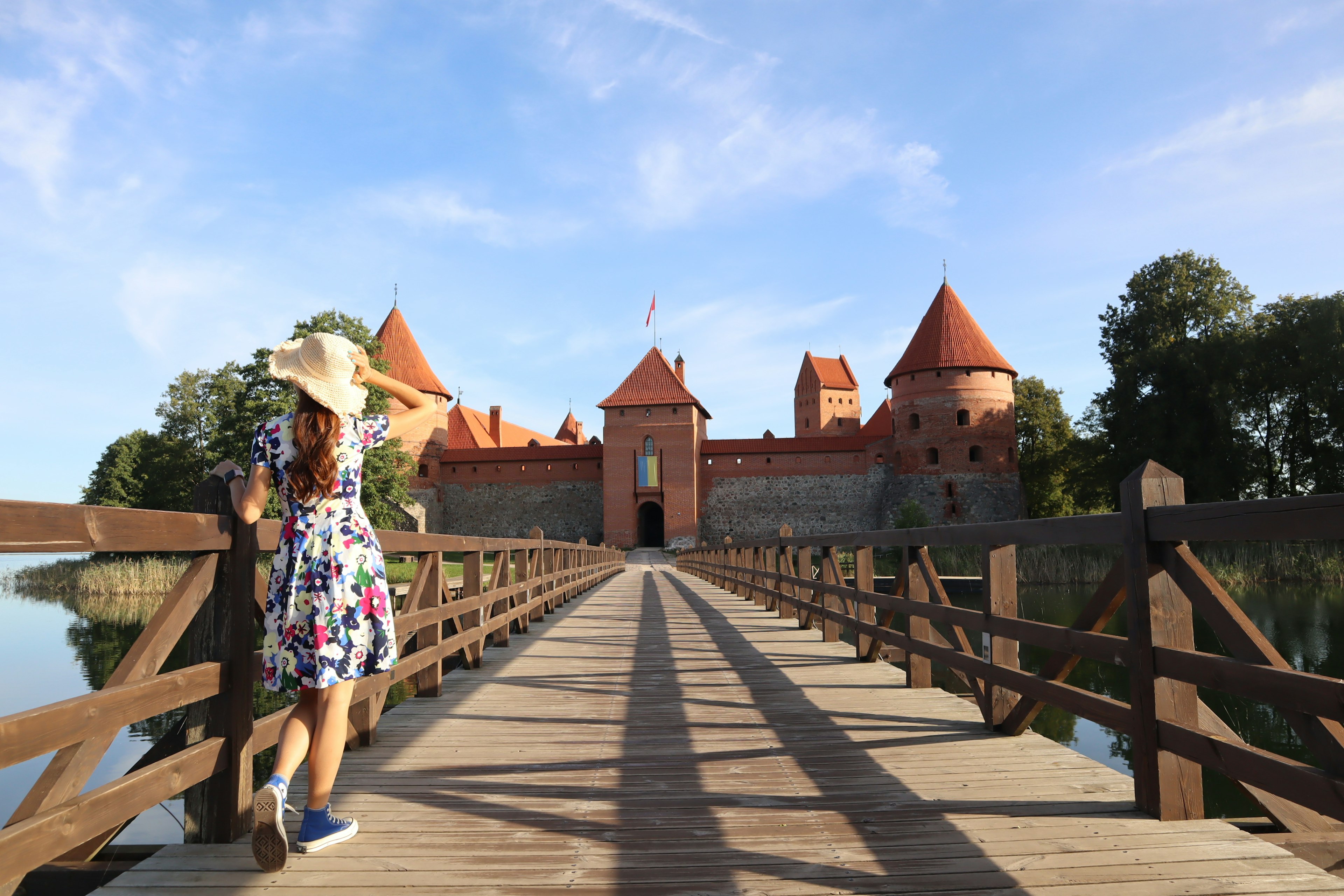 Una mujer caminando sobre un puente de madera hacia un hermoso castillo