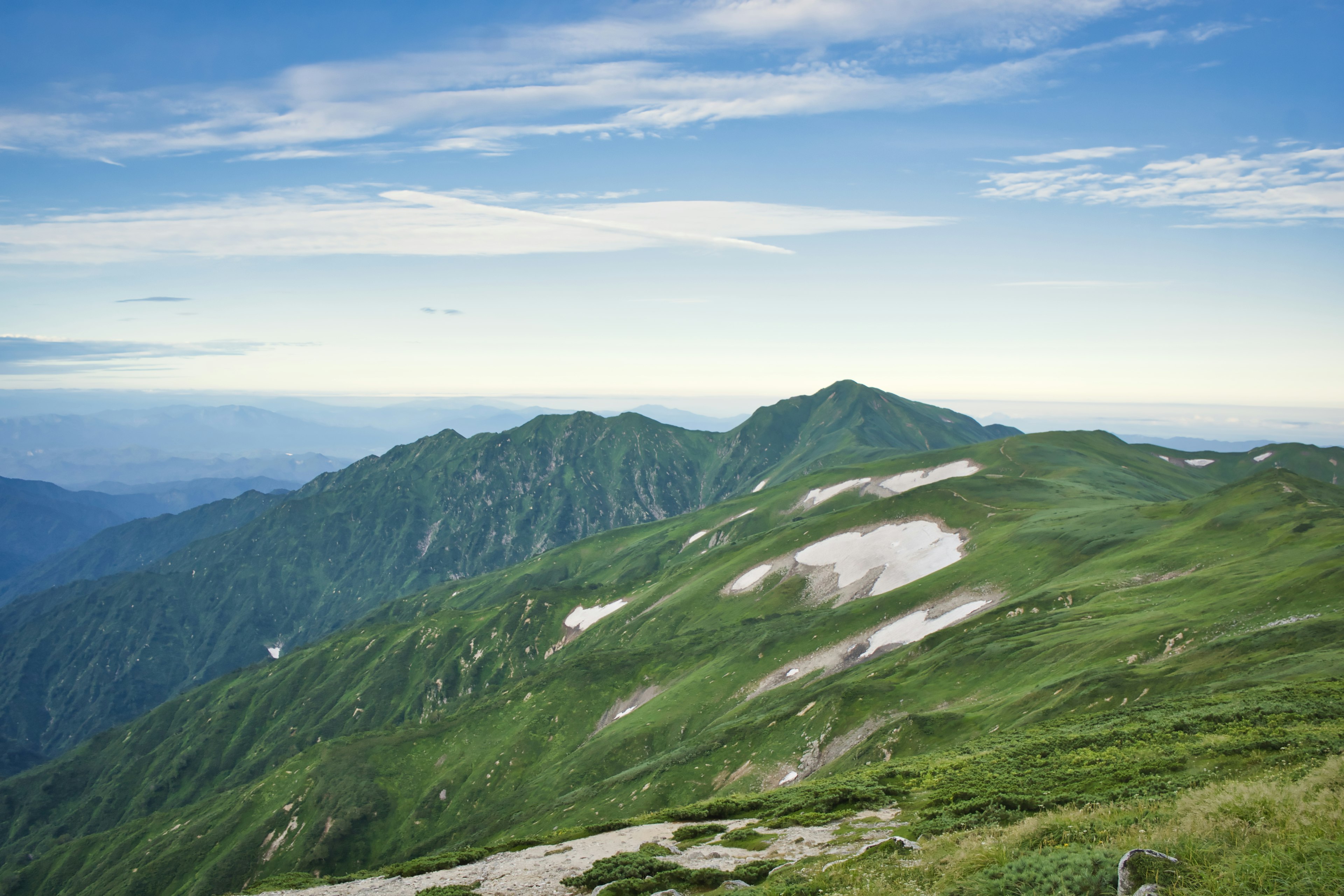 Üppige grüne Berge unter einem klaren blauen Himmel