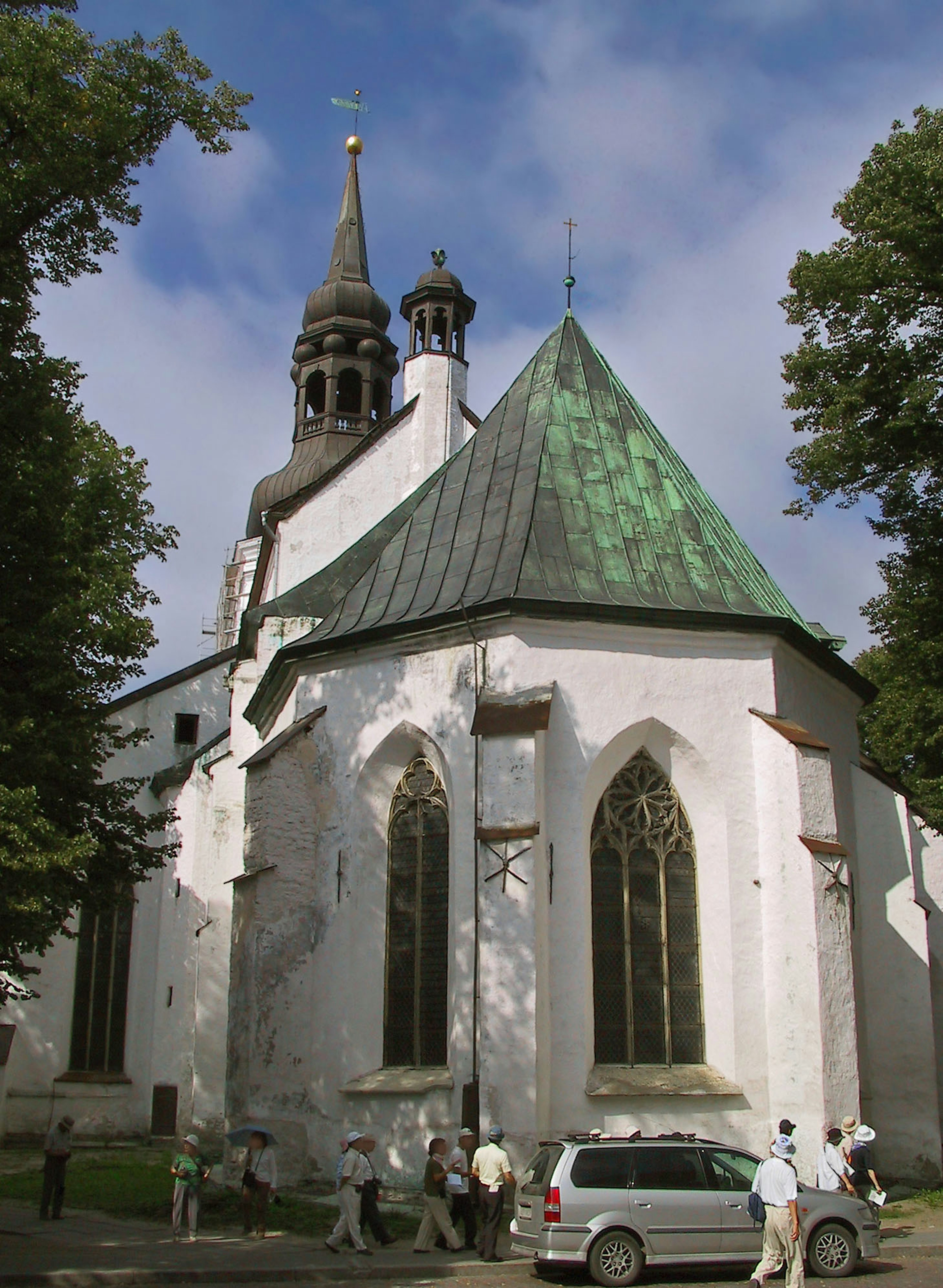 Beautiful exterior of a white church with a green roof surrounded by people