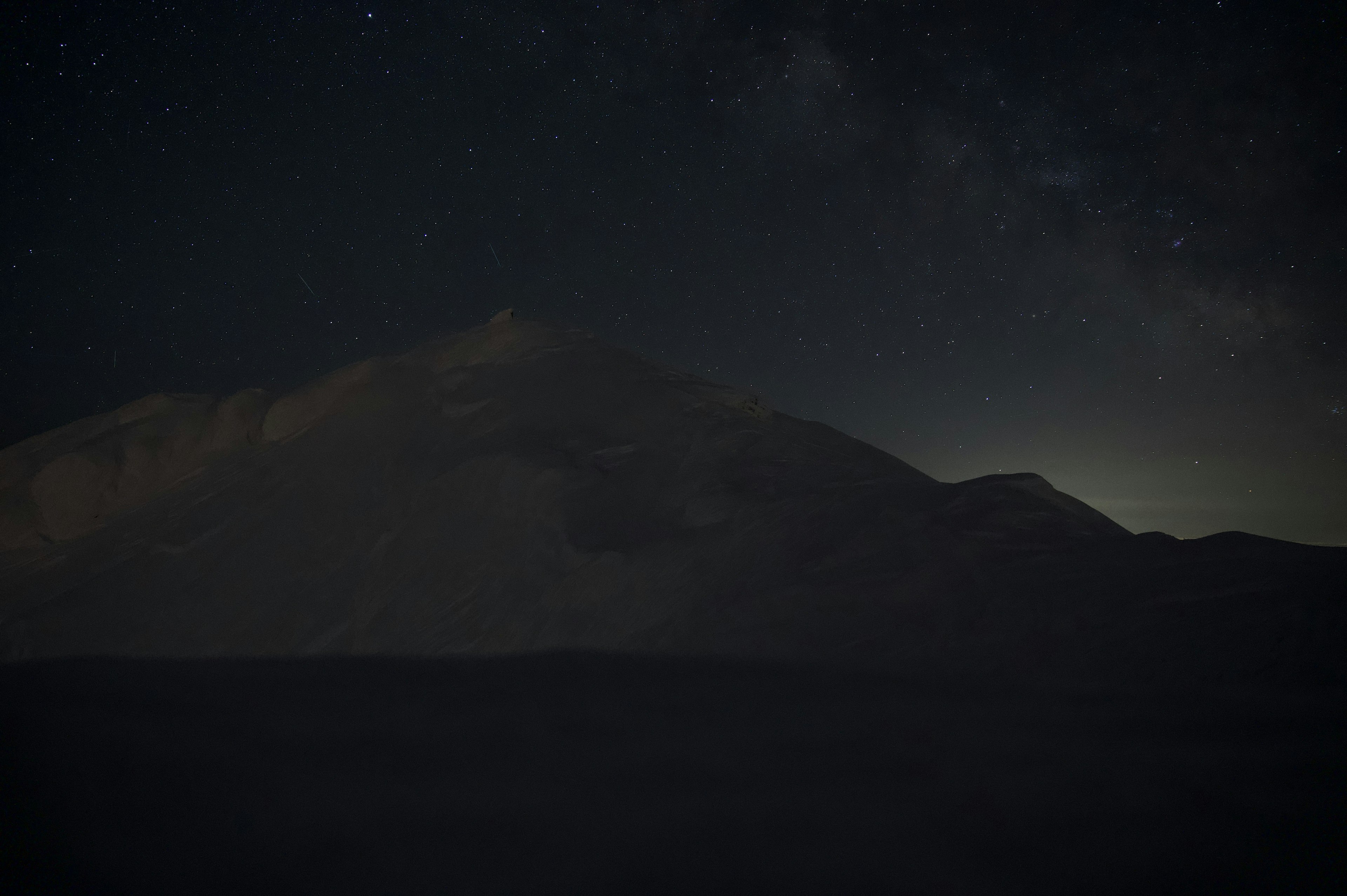 Siluet gunung gelap di bawah langit berbintang