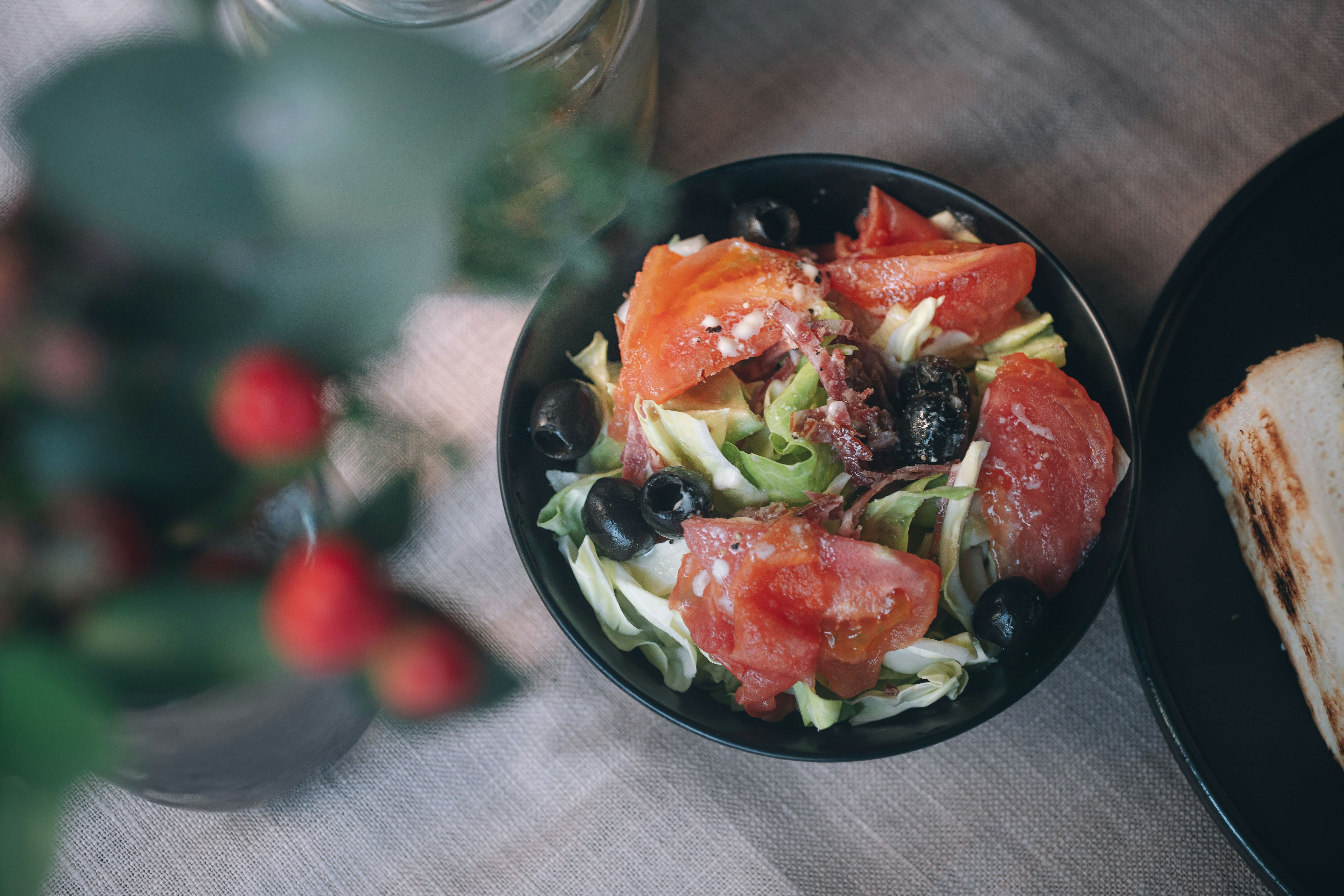 Fresh salad with tomato slices in a black bowl