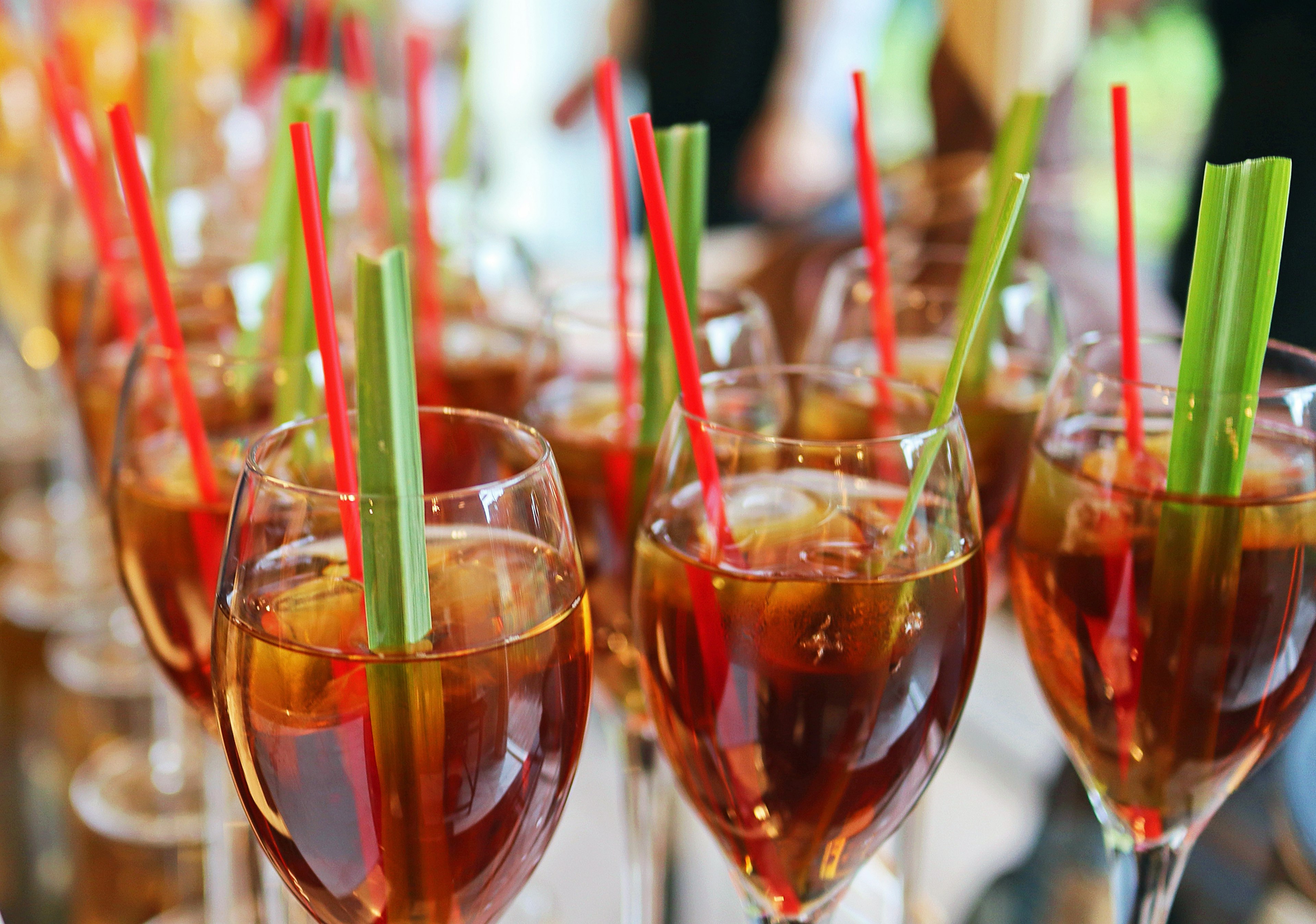 Row of cocktail glasses with colorful straws and celery sticks