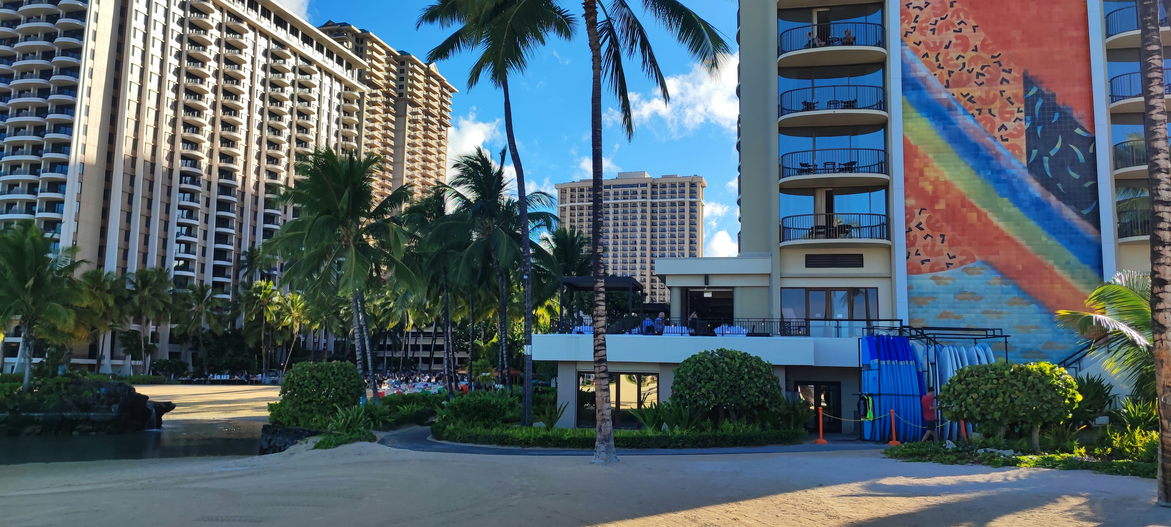 Vista de un resort de playa hawaiano con edificios altos y mural colorido