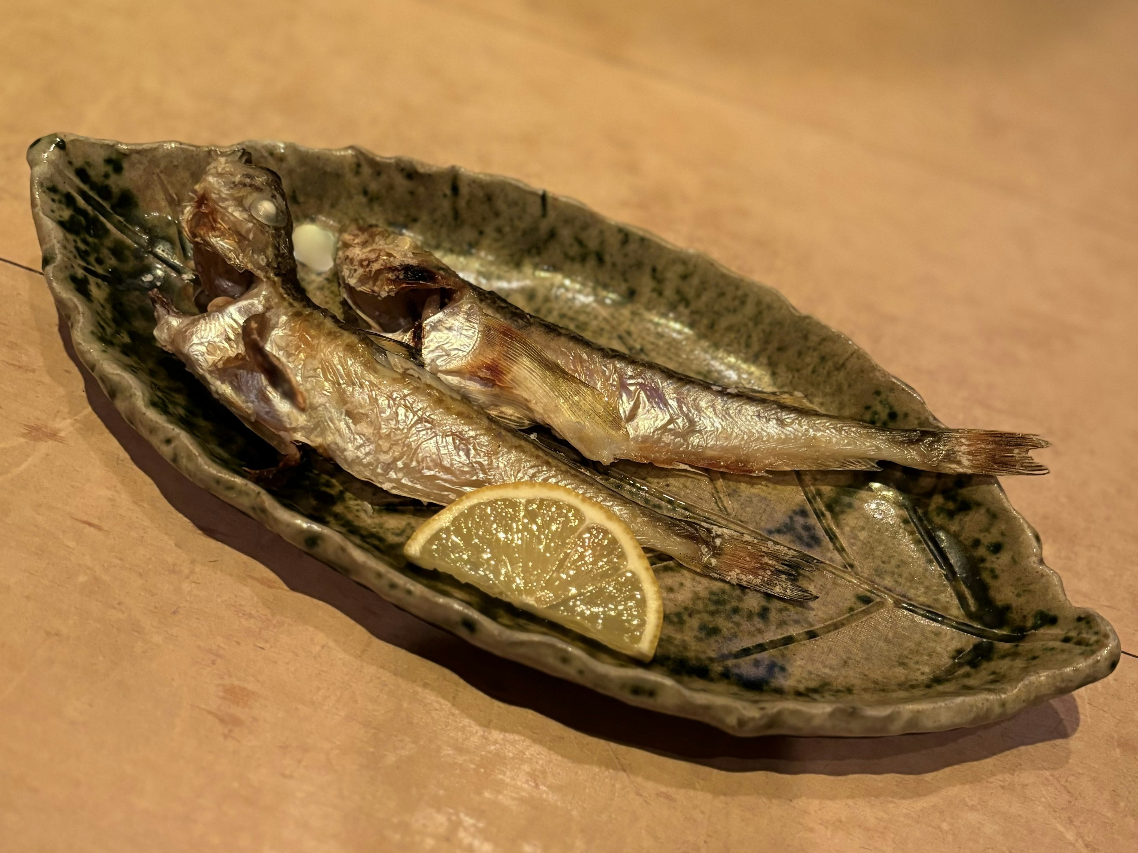 Pesce grigliato su un piatto a forma di foglia con una fetta di limone