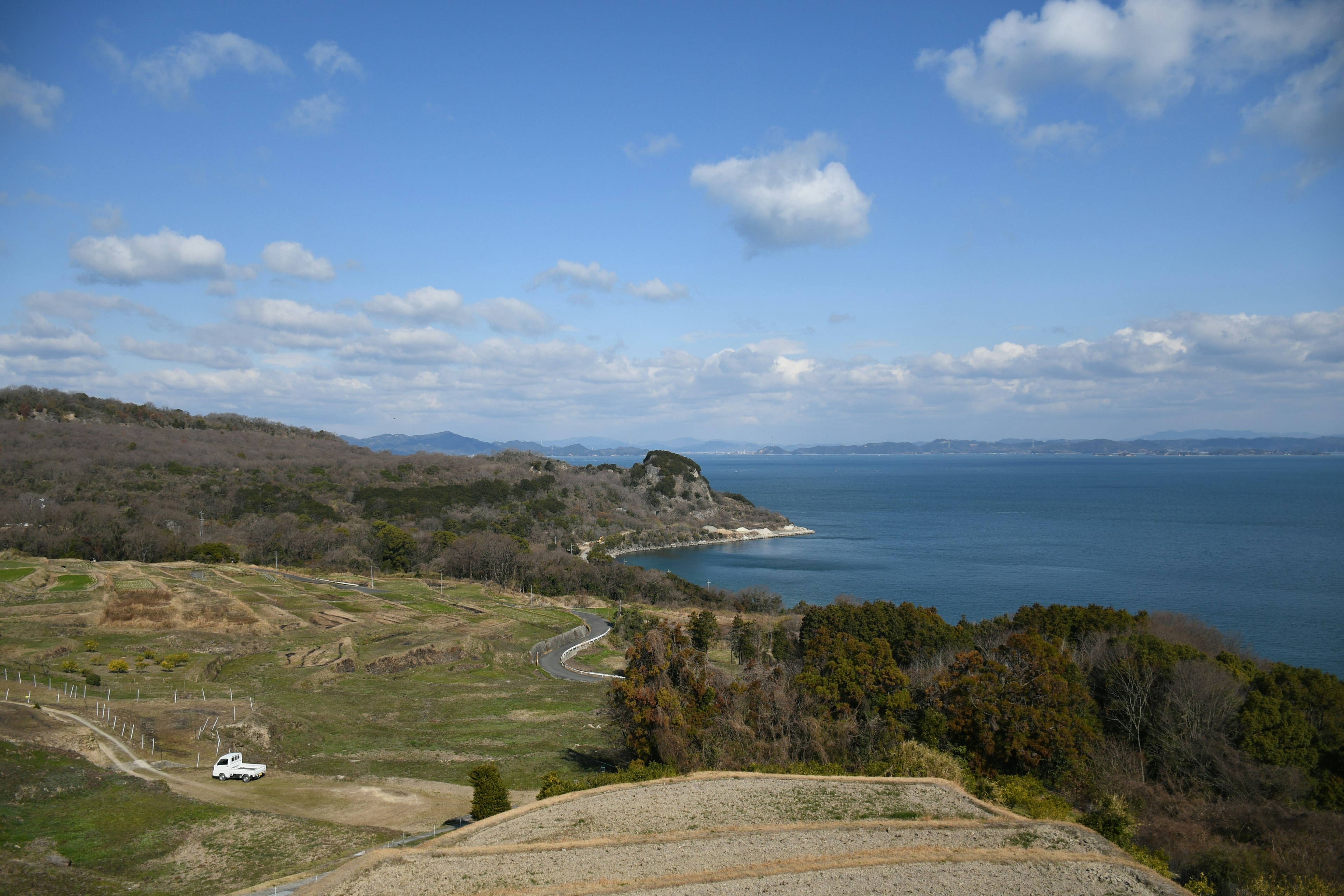 Vue panoramique de l'océan et des collines sous un ciel bleu avec des nuages