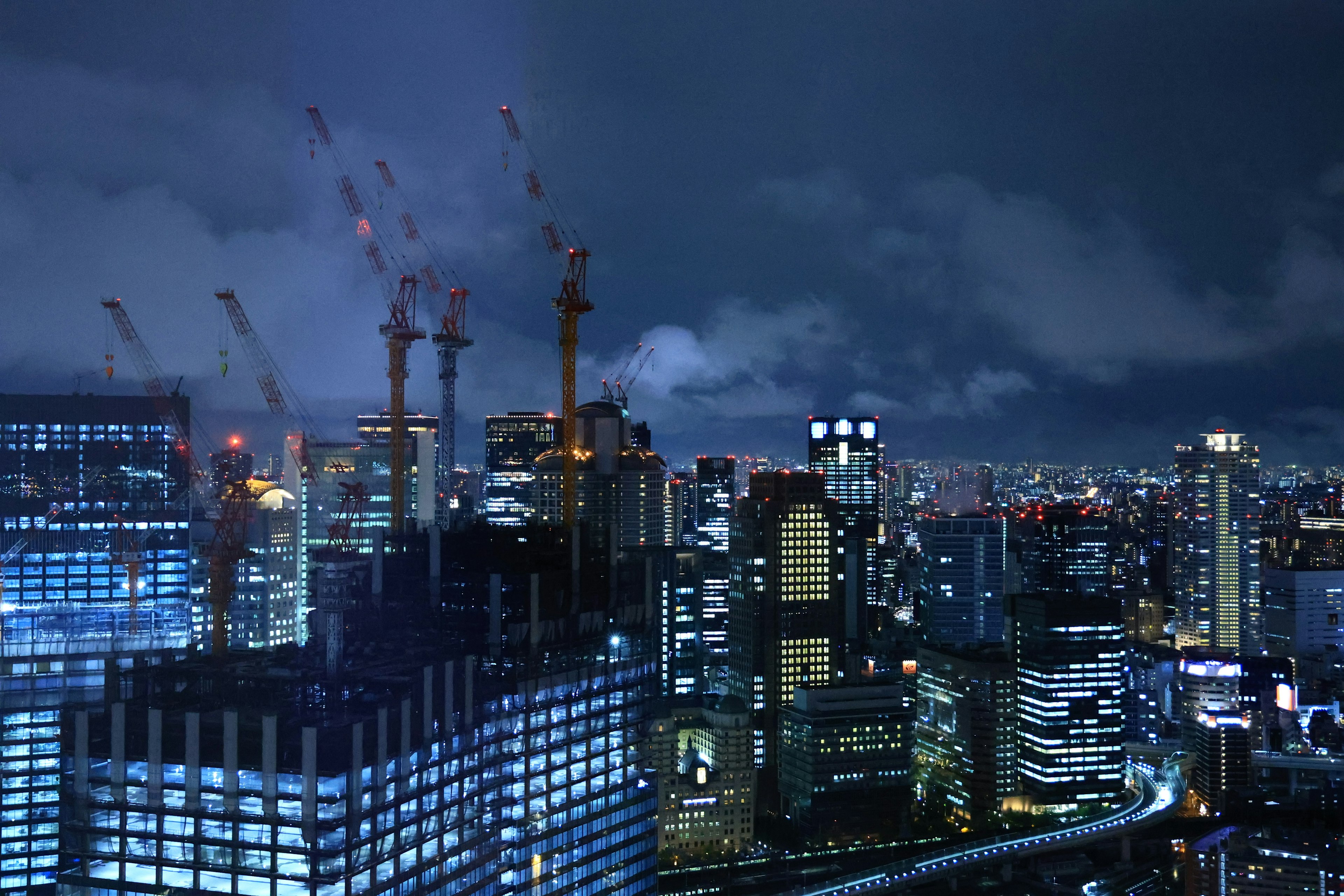 Paisaje urbano nocturno con rascacielos y grúas de construcción