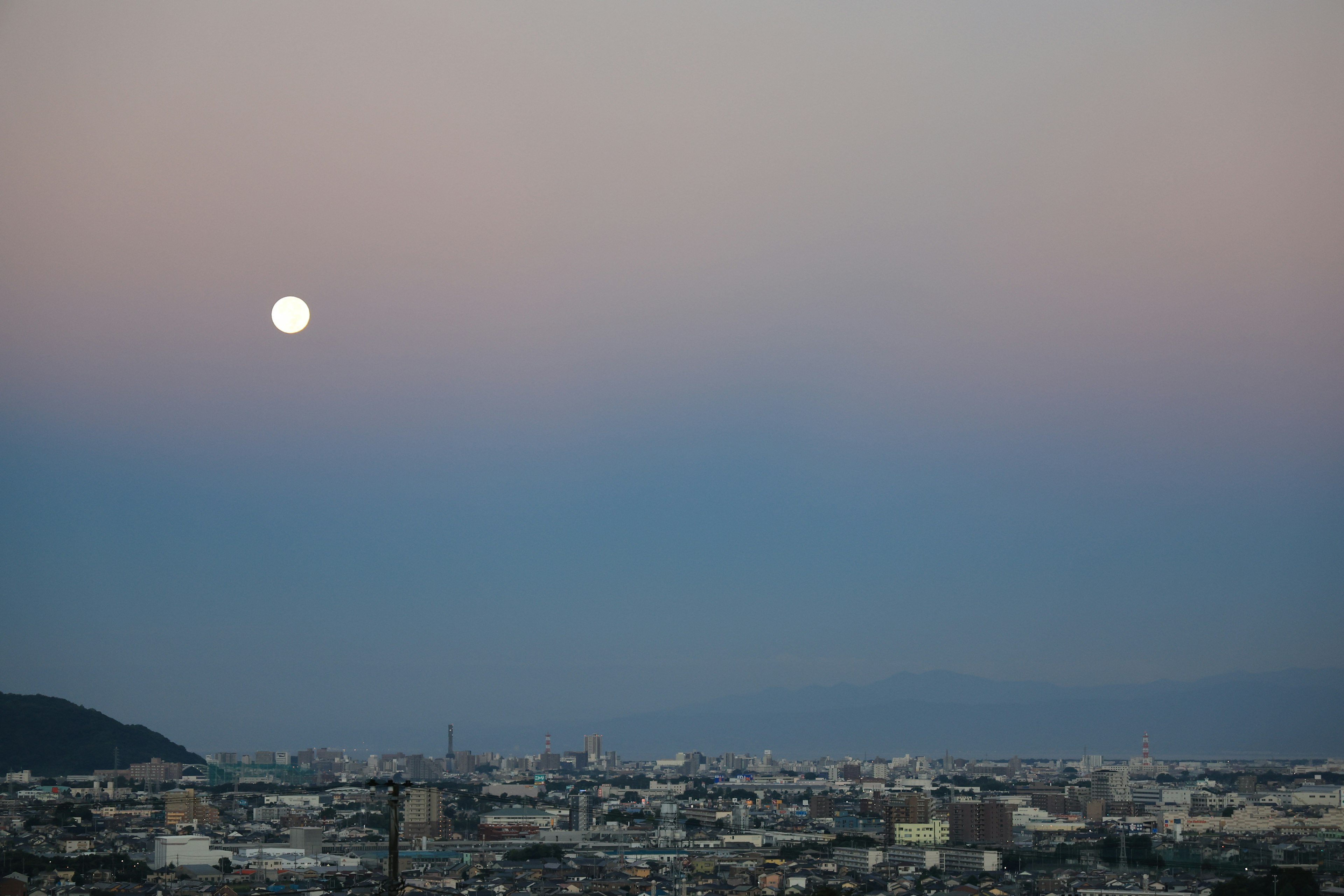 Bulan purnama di langit malam dengan latar belakang matahari terbenam gradasi