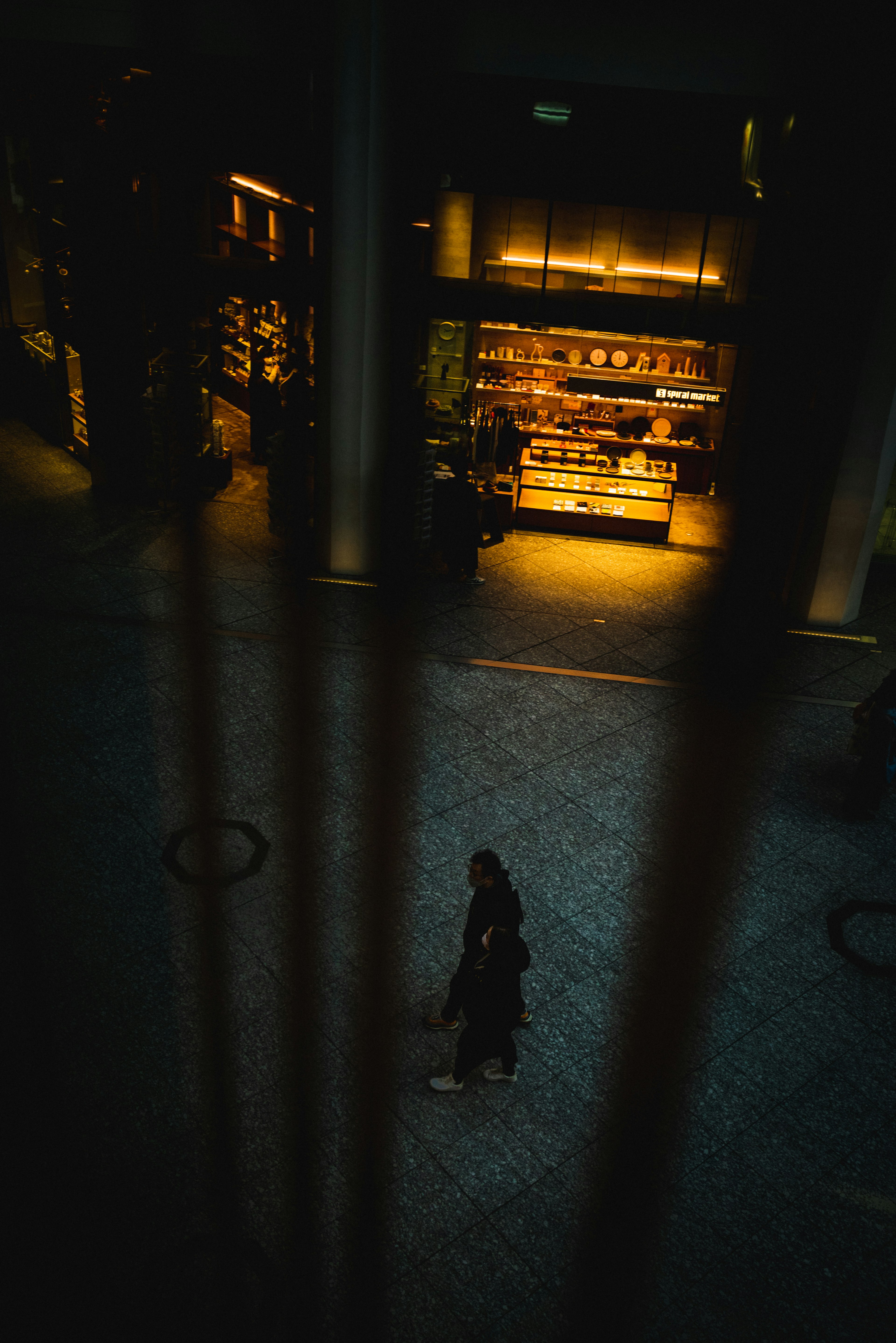 Eine Silhouette einer Person in einem dunklen Raum mit einem hell erleuchteten Caféregal