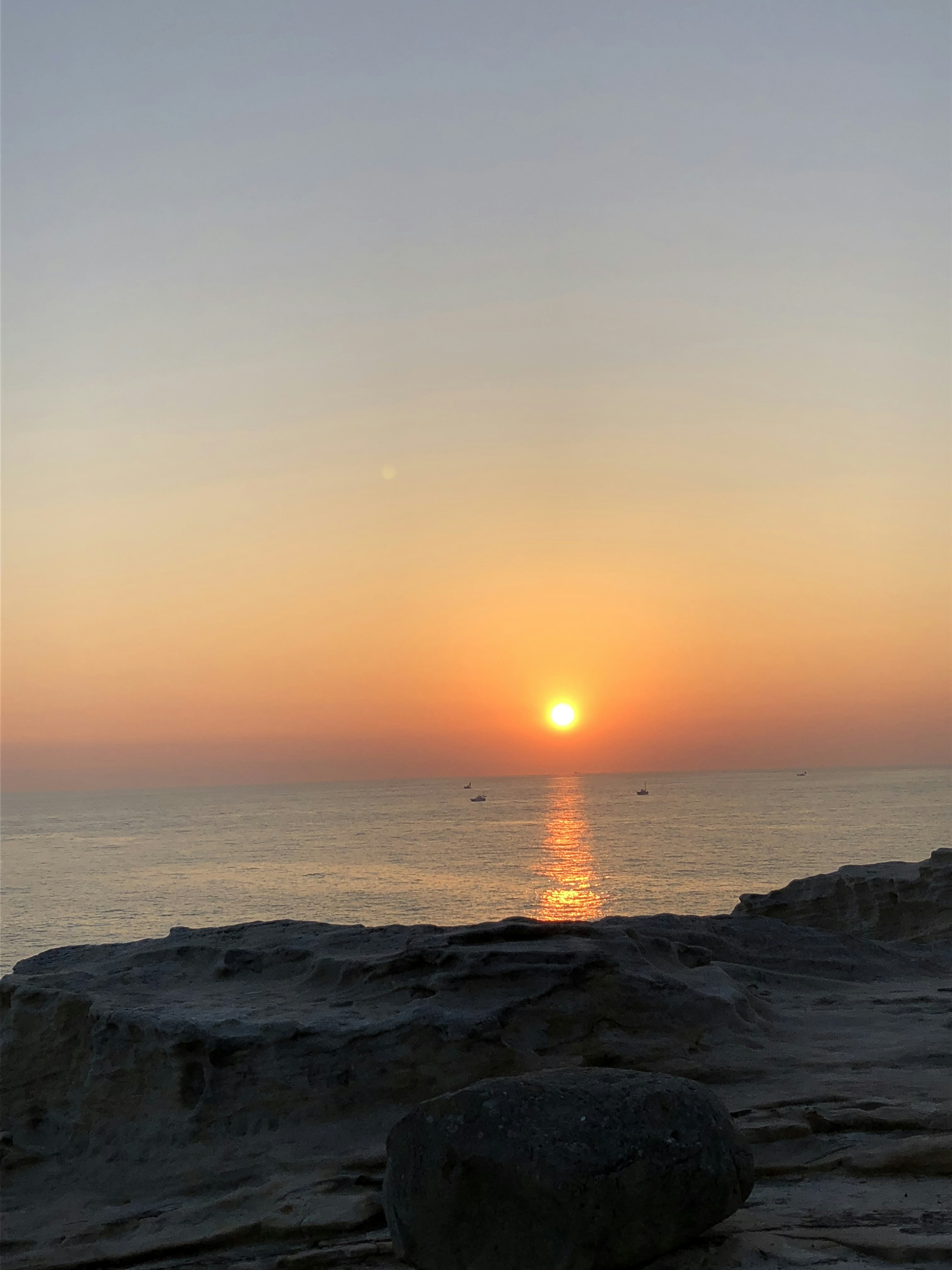 美丽的海上日落景观，前景有岩石