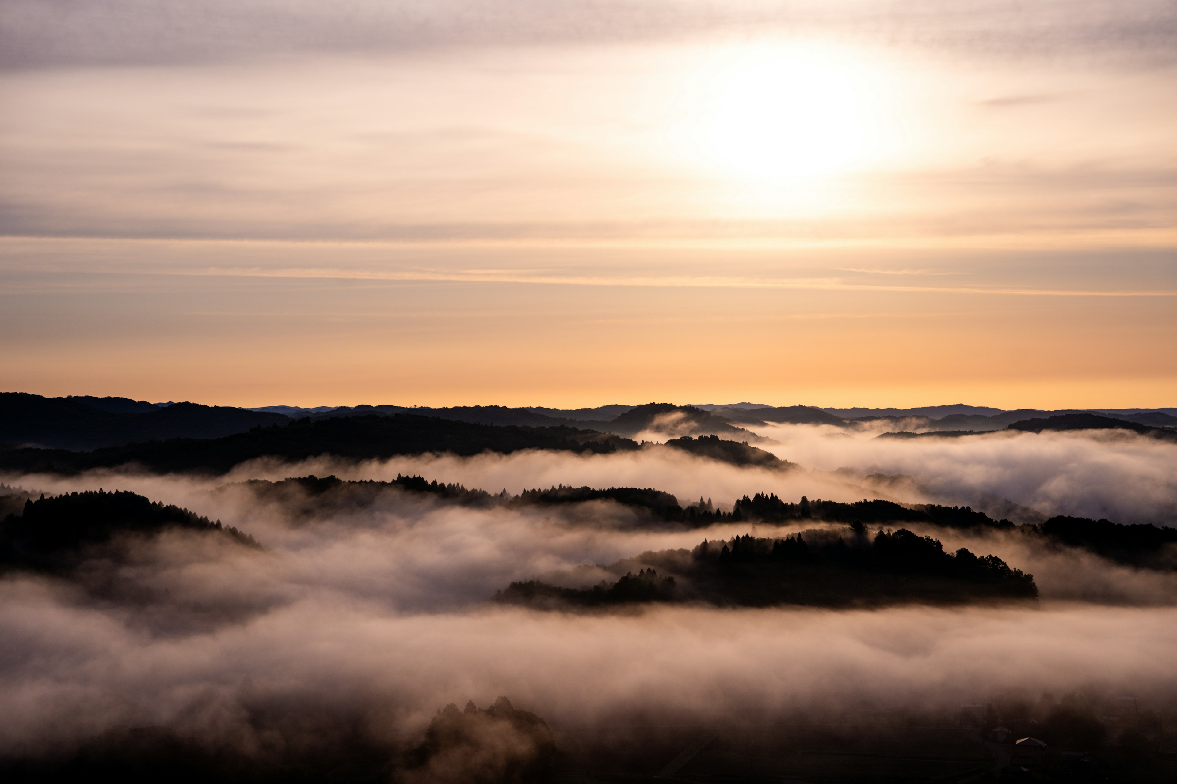 Sunrise over misty hills with soft clouds