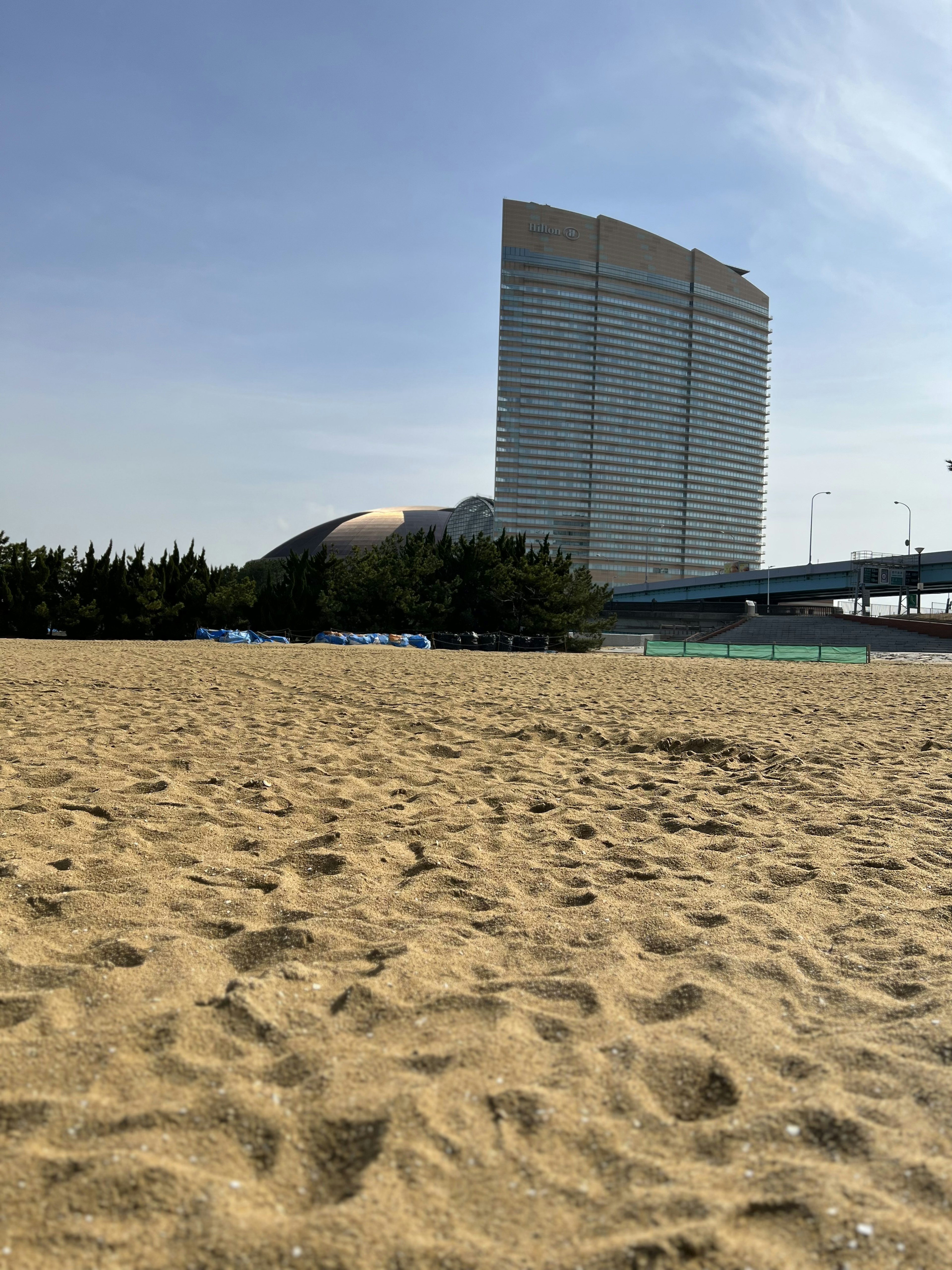 砂浜と高層ビルの風景 橋と木々が見える