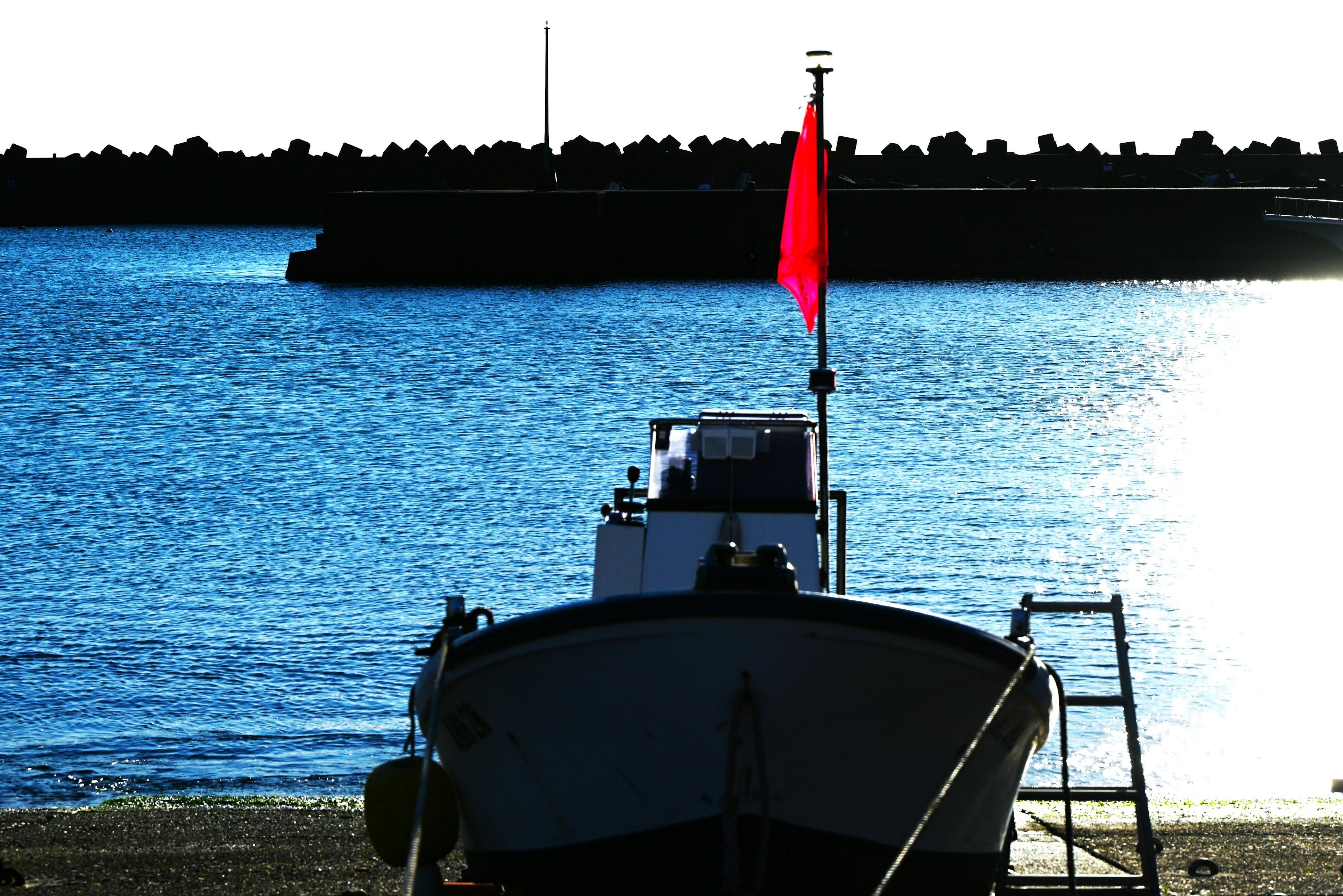 Small boat with a red flag facing the water