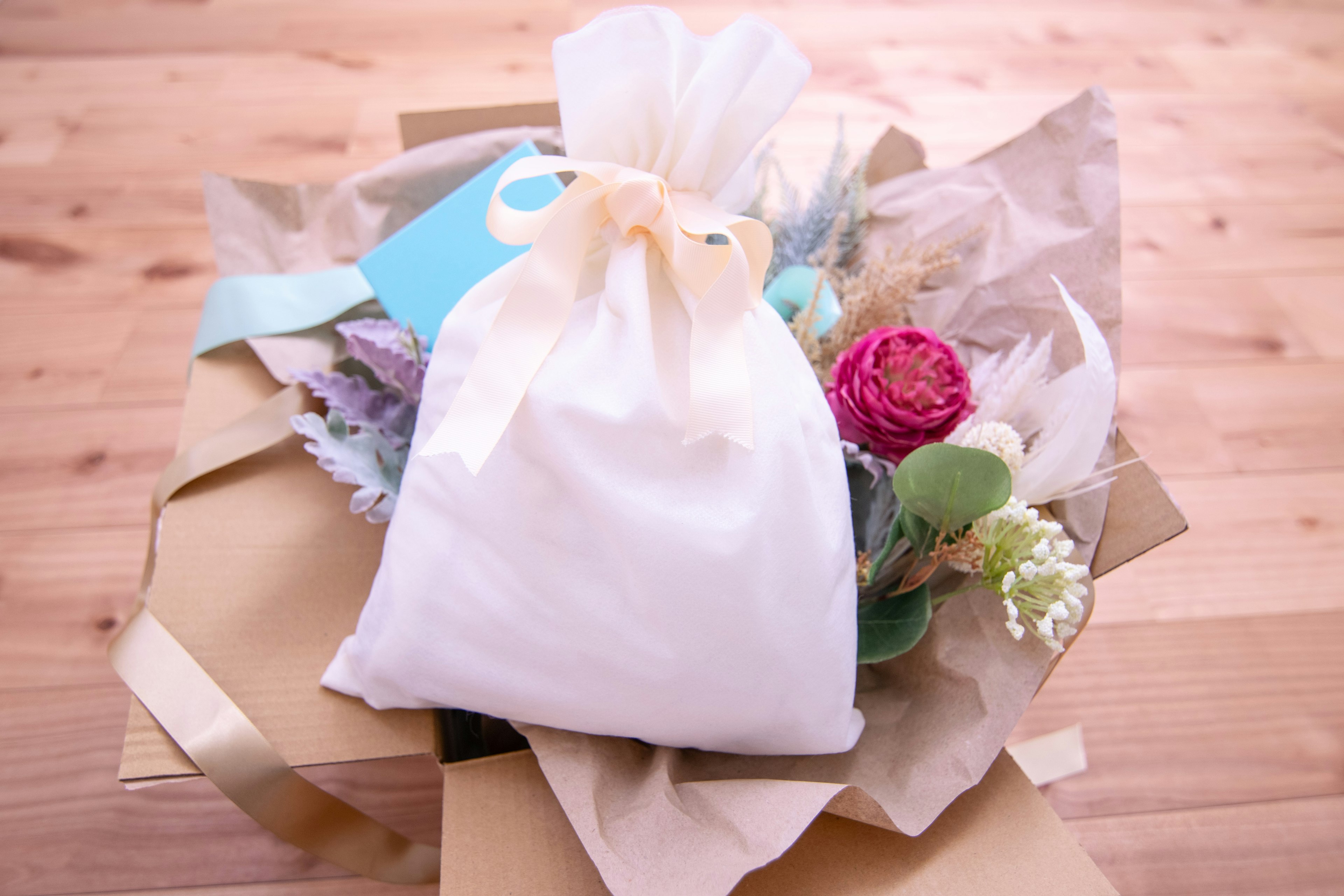 Un cadeau avec un bouquet et un sac blanc est visible dans une image aux tons chauds