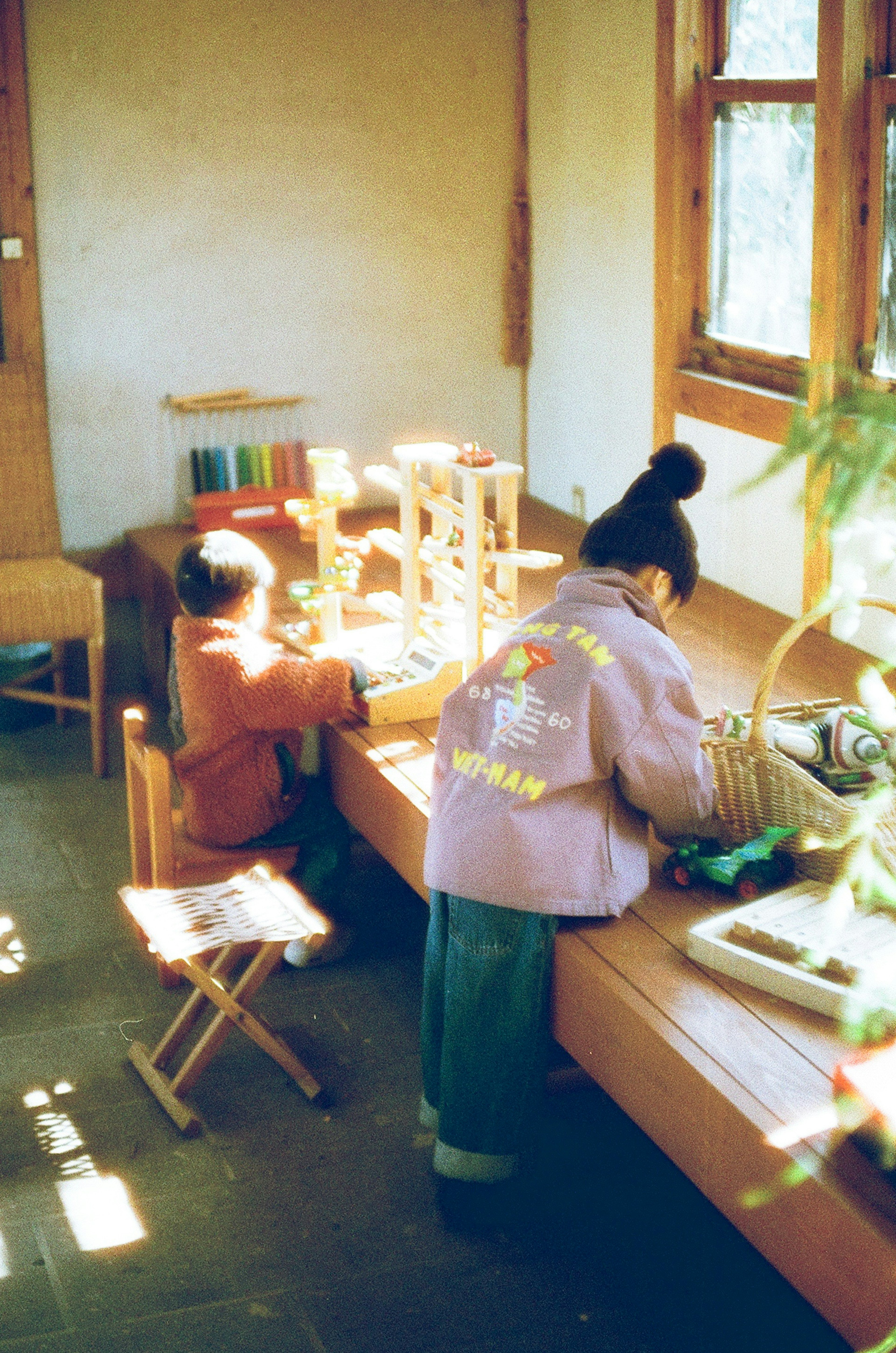 Kinder spielen an einem Holztisch in einem gut beleuchteten Innenraum mit natürlichem Licht