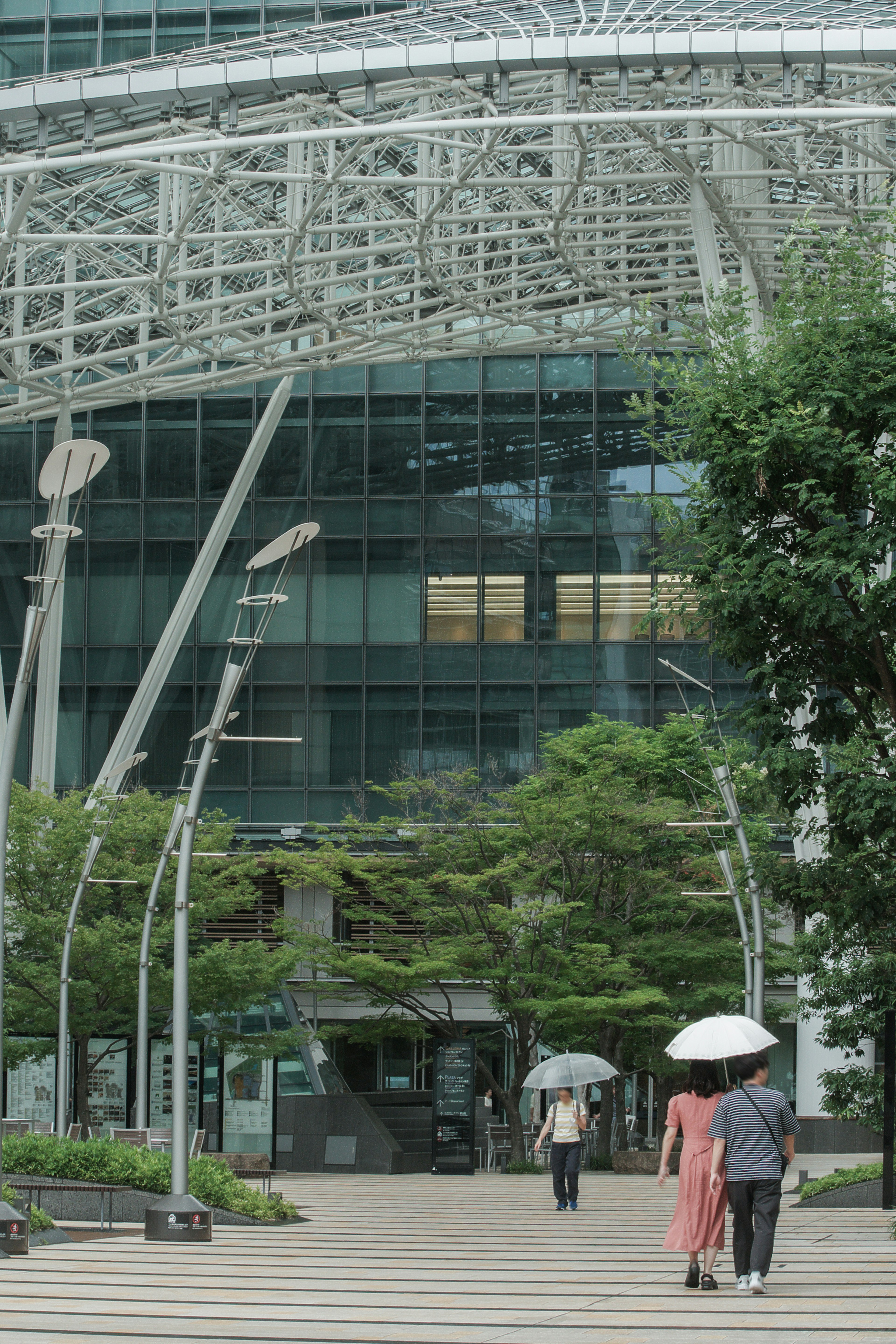 People walking in front of a modern building with greenery