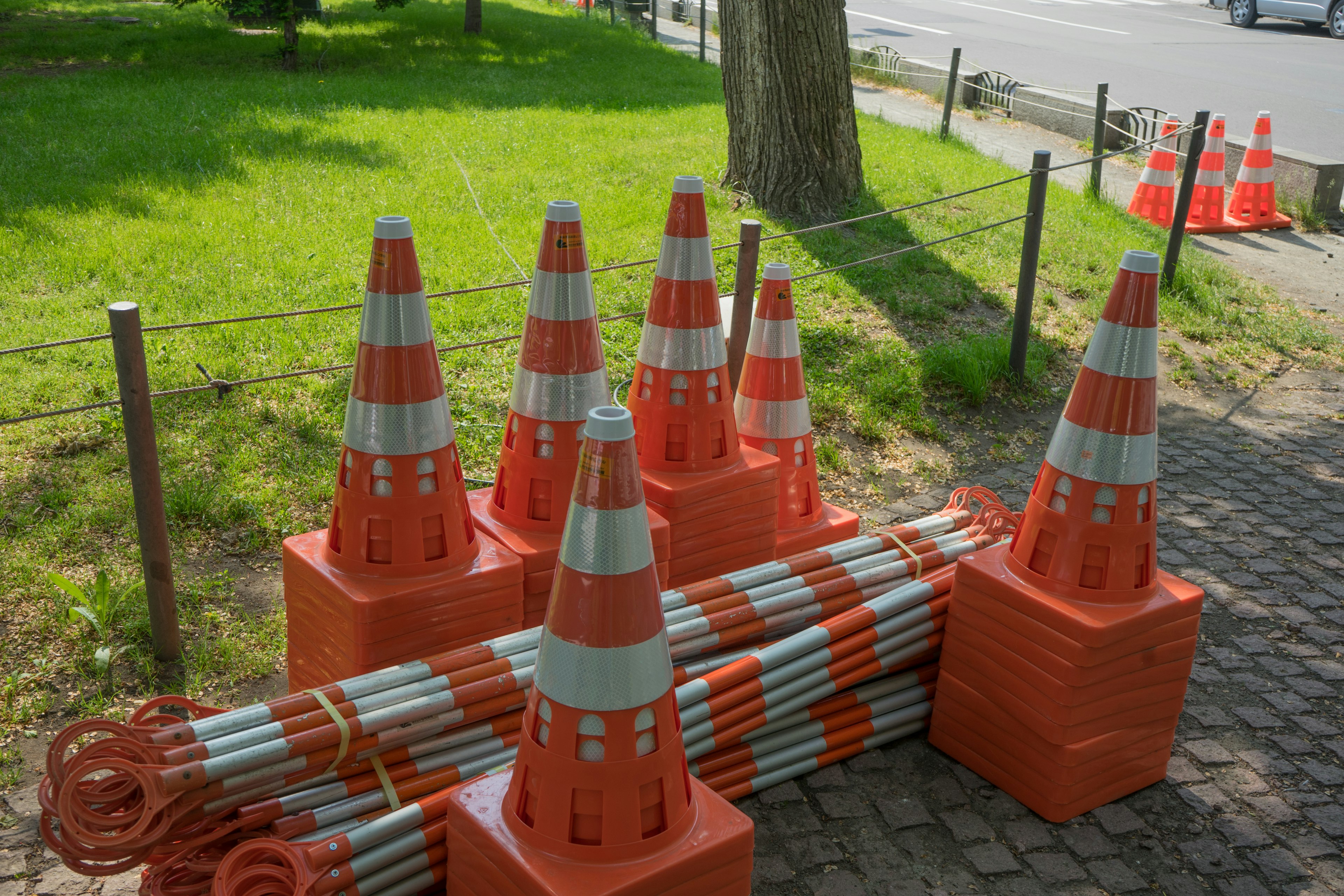 A stack of orange traffic cones with striped barriers beside them