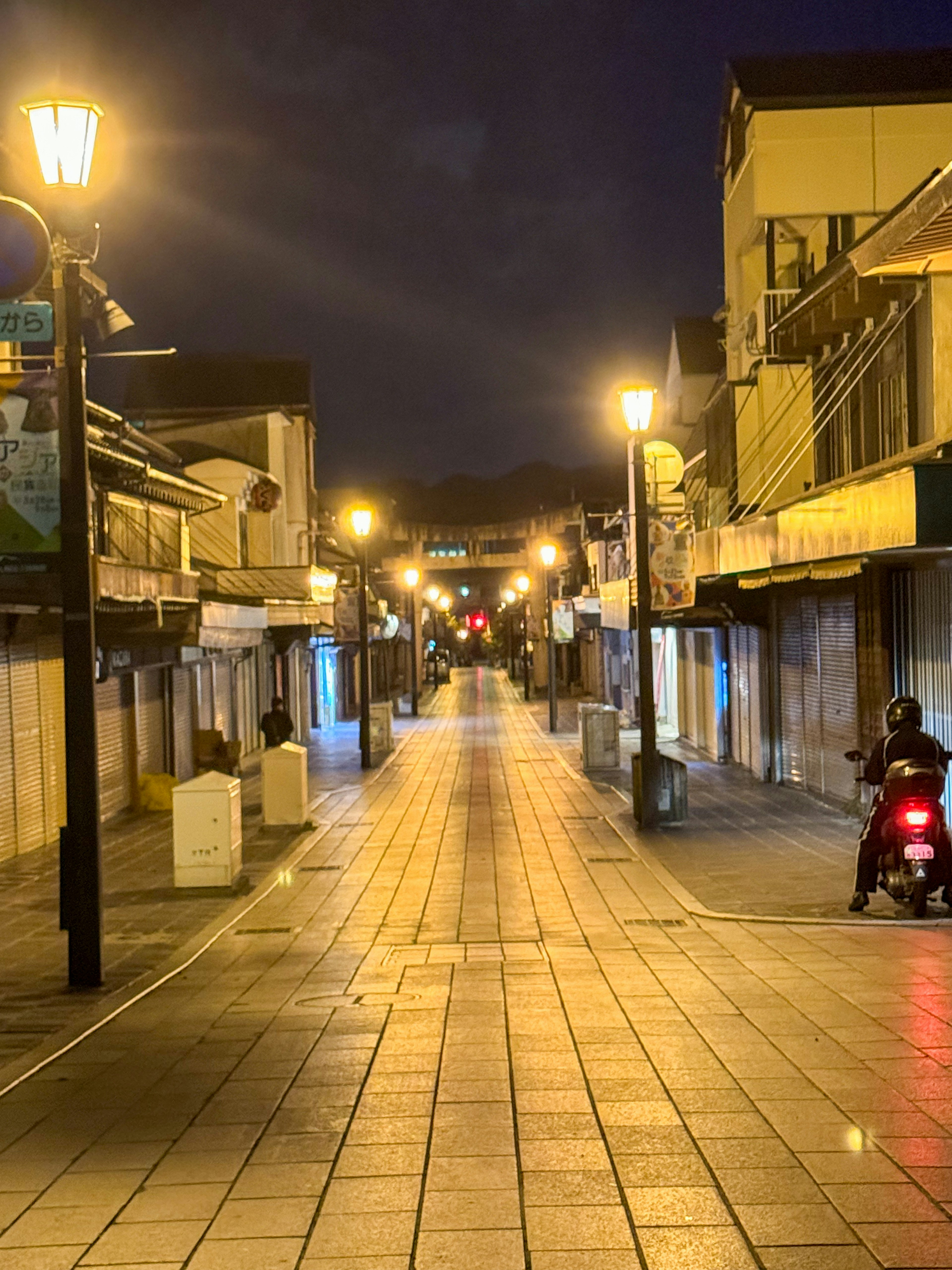 Quiet street at night with streetlights and closed shops