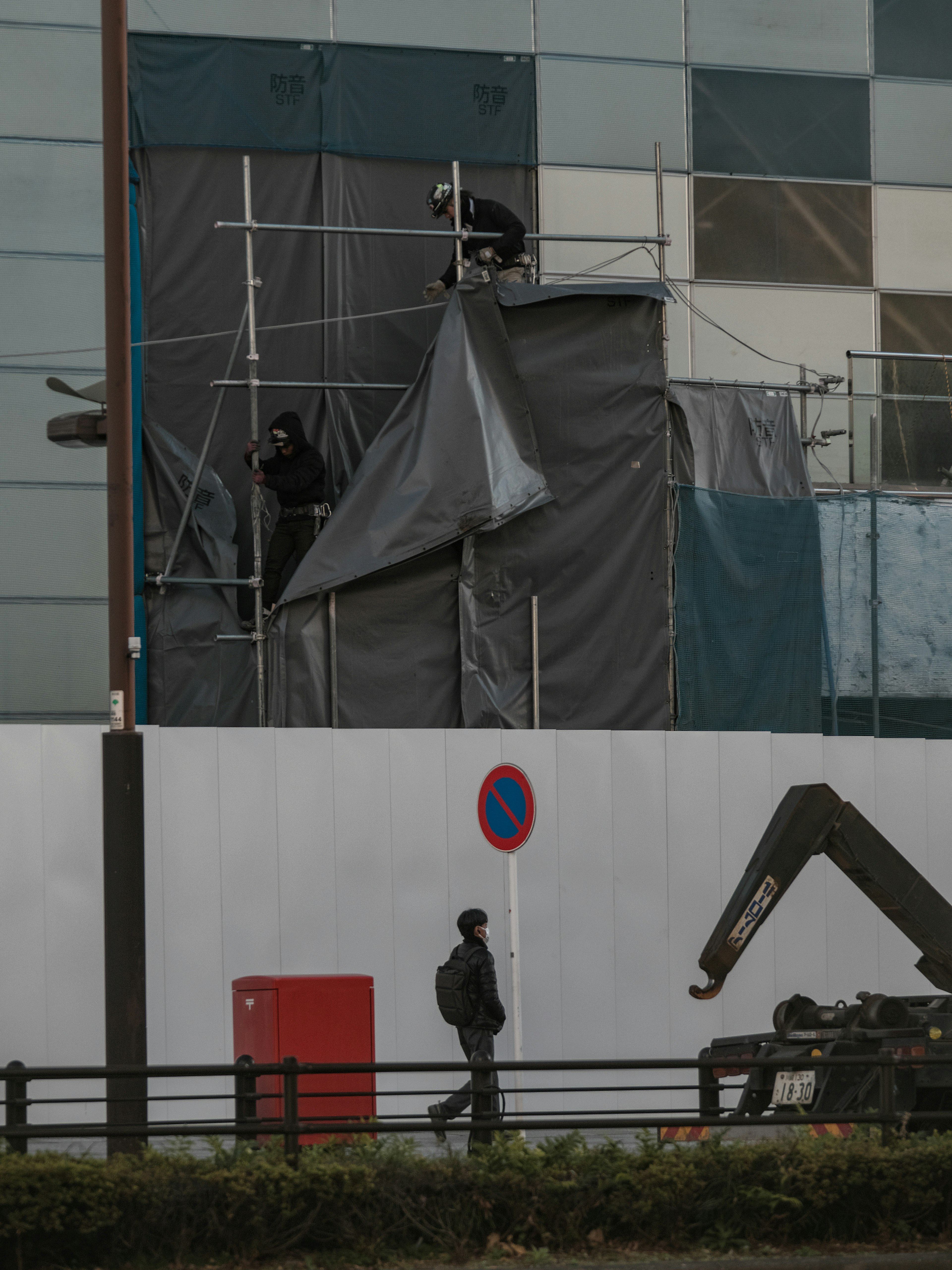 Image montrant des travaux de construction sur un bâtiment avec un passant