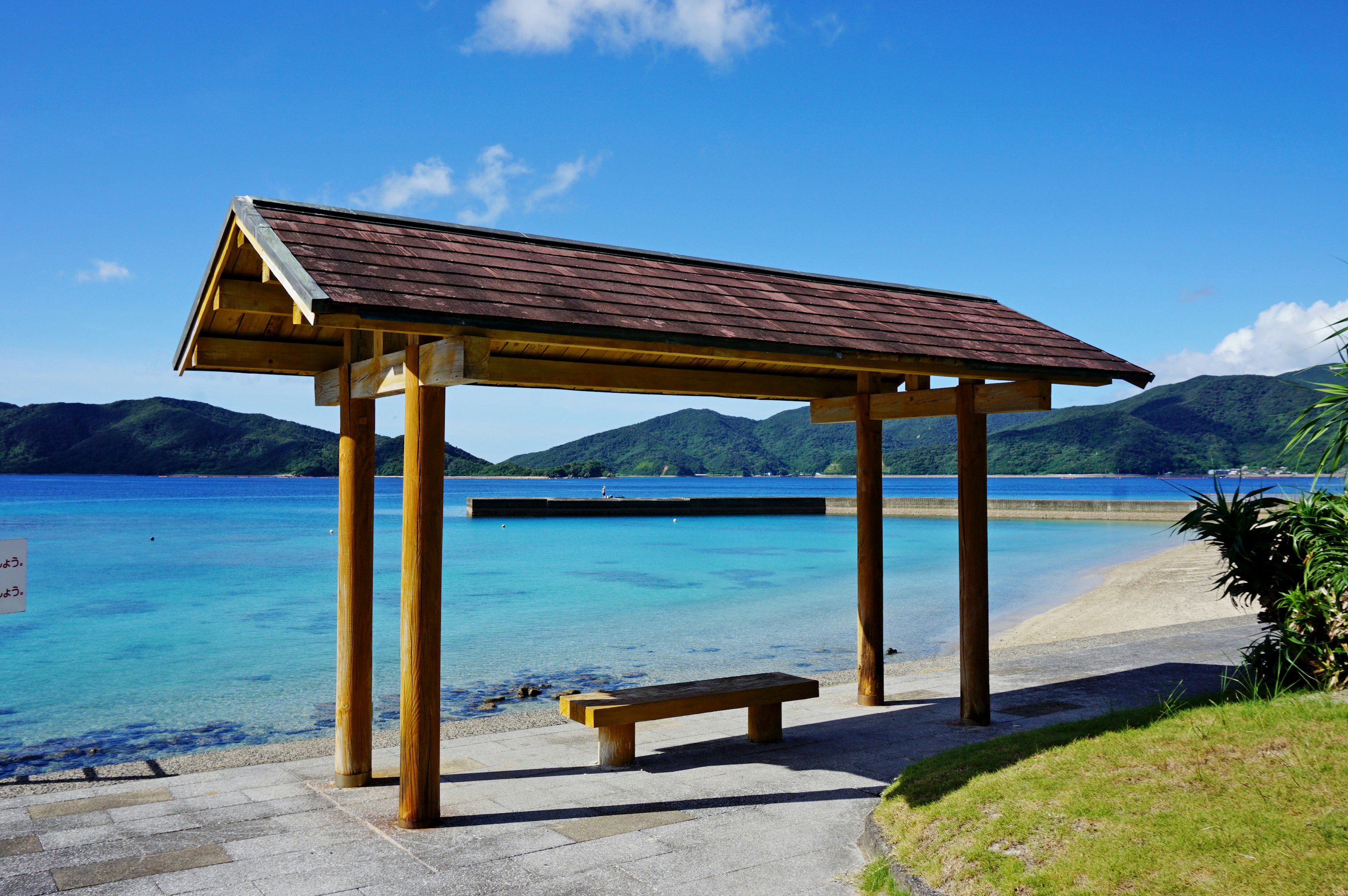 美しい海と山の景色を背景にした木製のベンチと屋根付きの休憩所