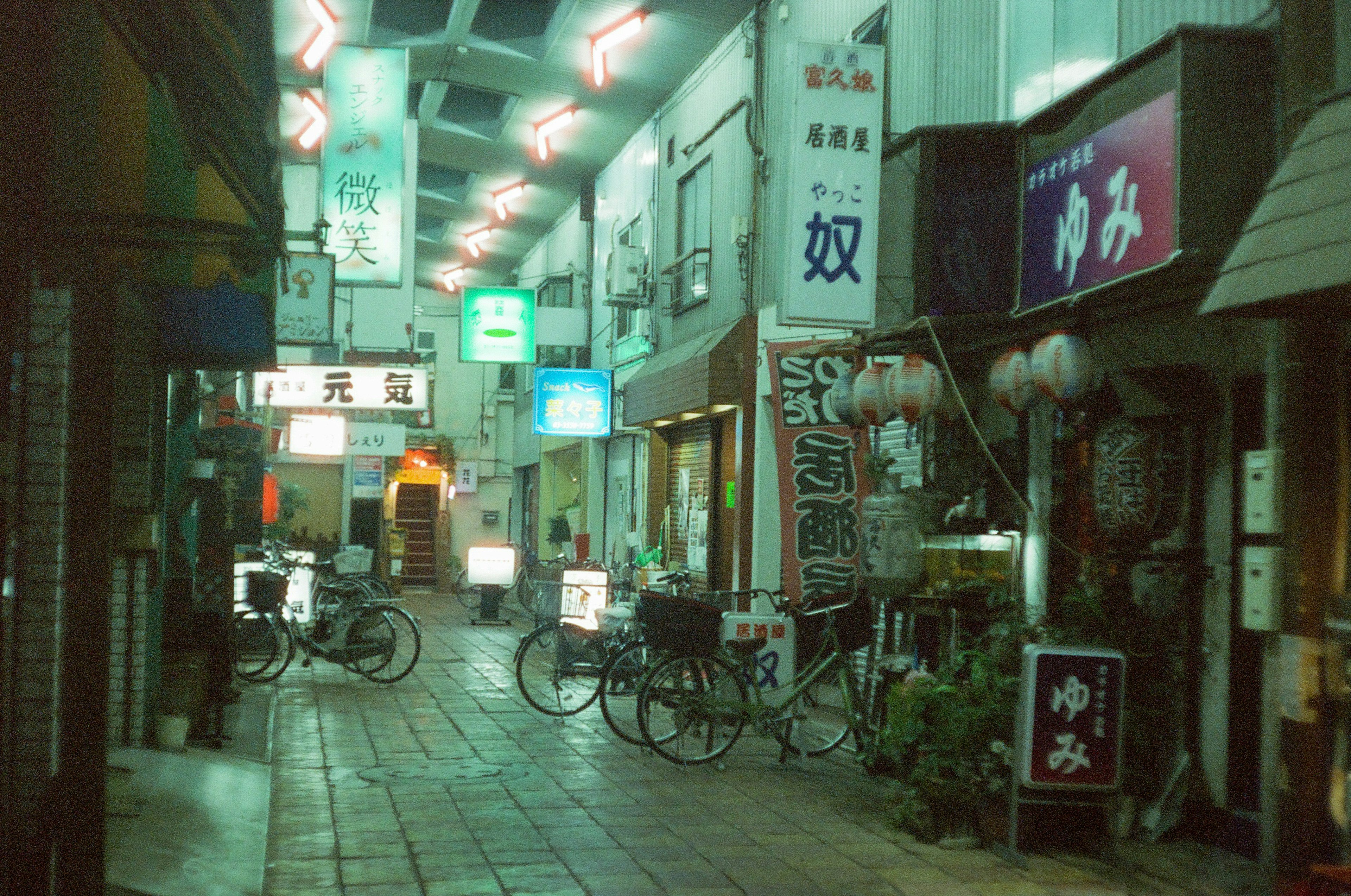 Vista nocturna de una calle comercial con restaurantes y bicicletas