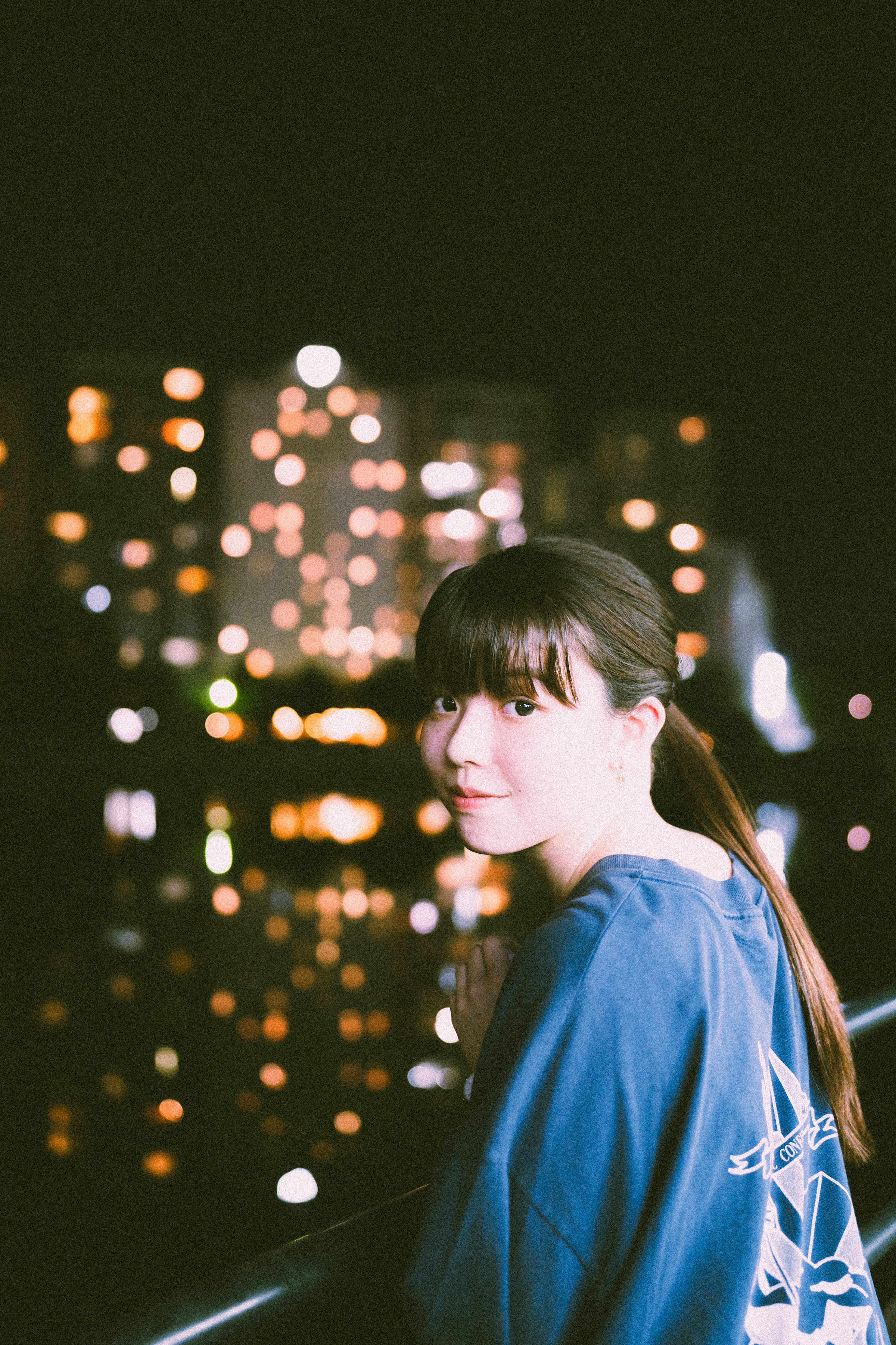 Portrait d'une femme avec un arrière-plan de nuit urbaine portant une chemise bleue