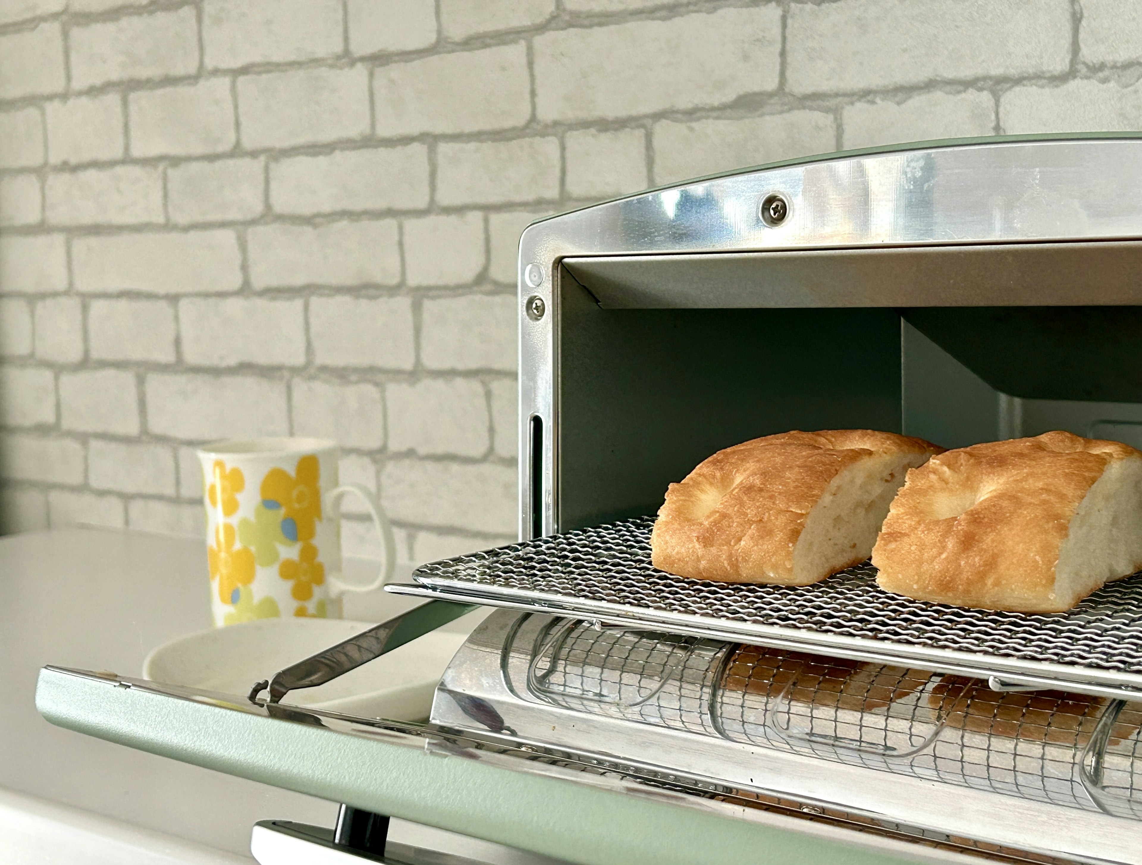 Freshly baked bread in a toaster with a white brick wall background