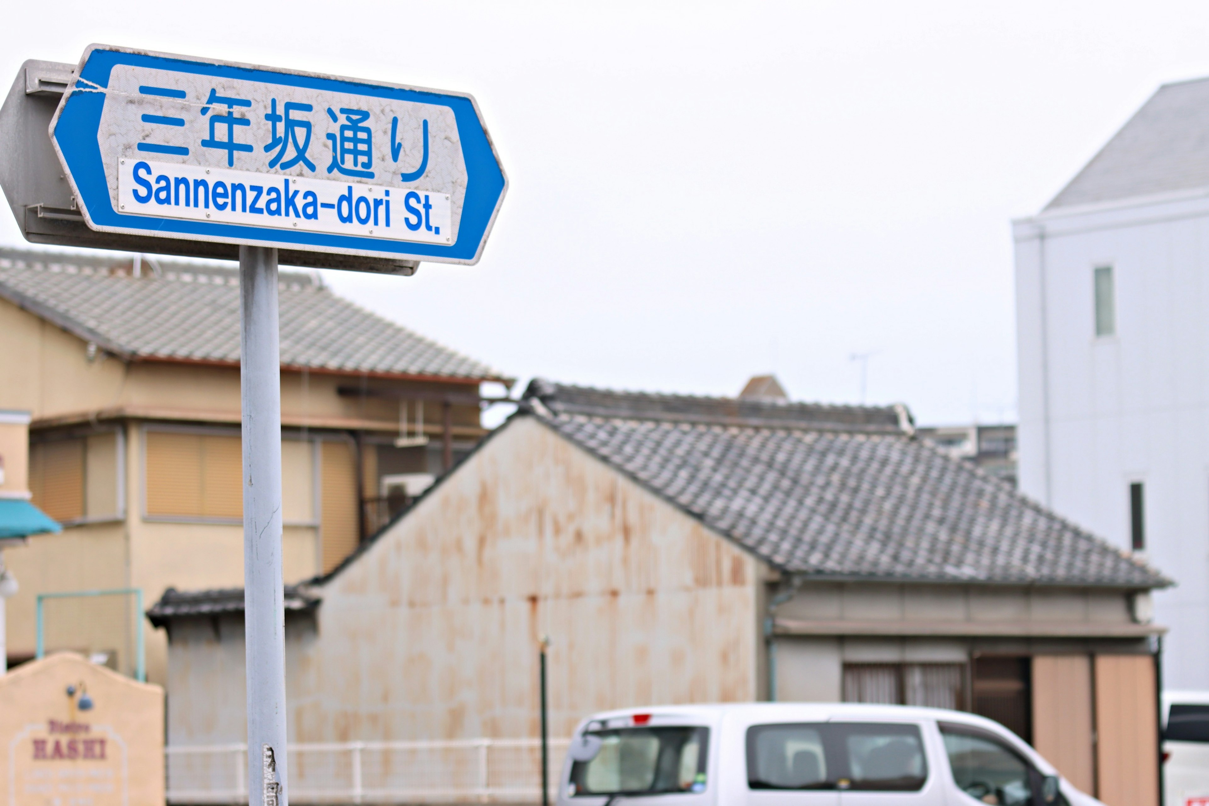 Blue street sign for Sannenzaka-dori with surrounding buildings